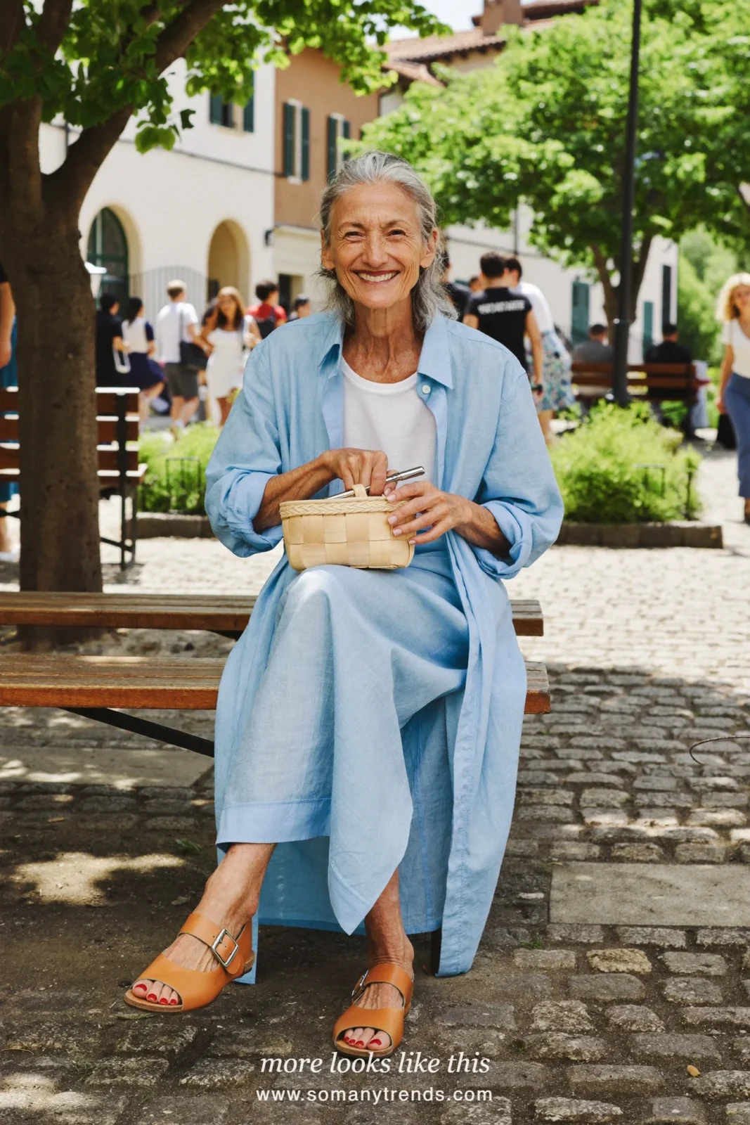 Woman in her seventies in a long pale blue linen shirtdress and leather sandals, look 15