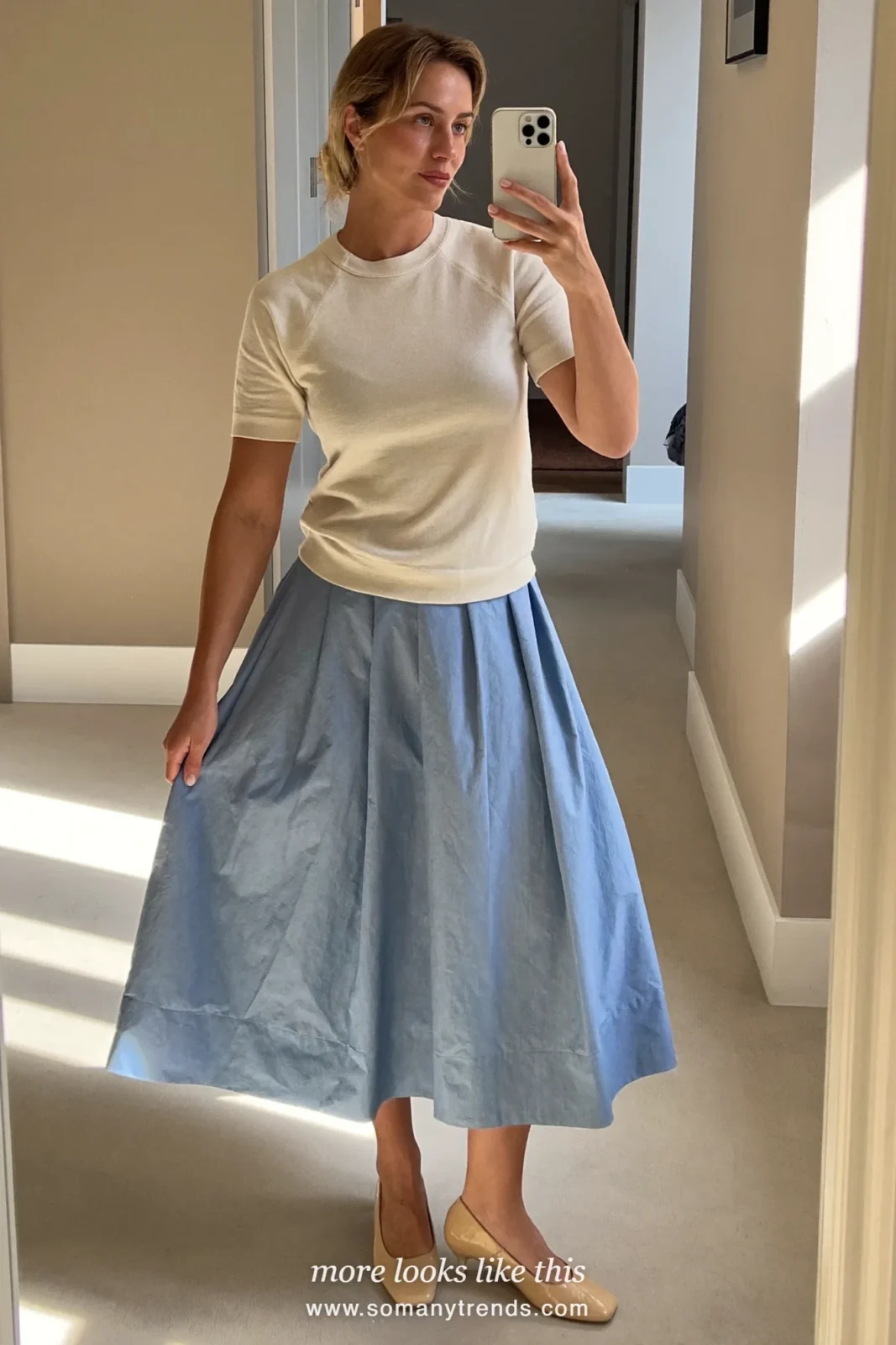Mirror selfie of a woman in a cream short-sleeve knit, a sky blue A-line midi skirt and nude heels in a hallway, Easter church outfit 8