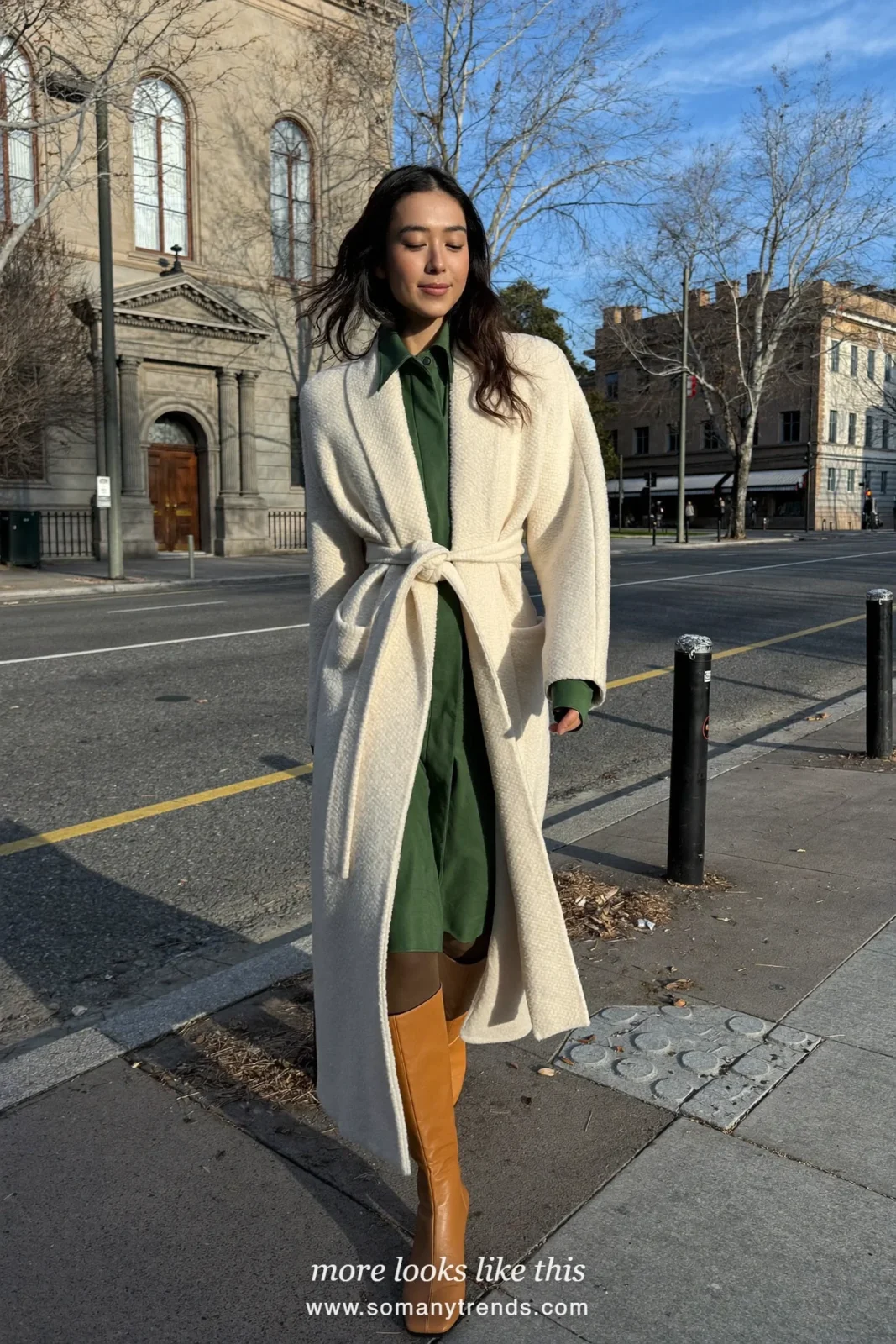 Woman in a long ivory belted coat over a forest green midi dress with tan boots, Easter outfit 26