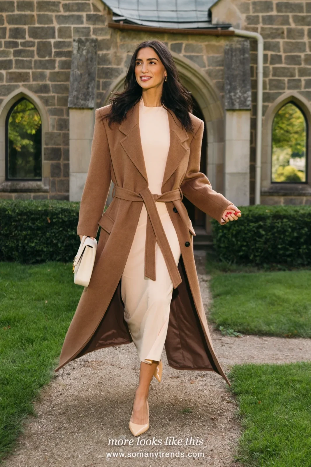 Woman in a long belted camel coat over a peach midi dress with sleeves and nude pumps, Easter church outfit 13