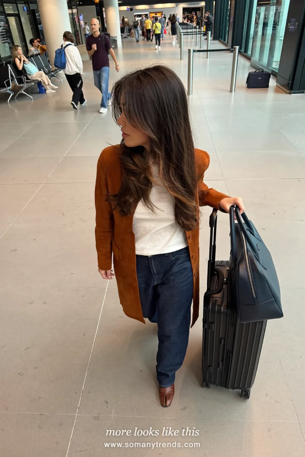 Woman in a cognac suede jacket, white tee, dark straight jeans and brown ankle boots at a gate, work conference outfit 2