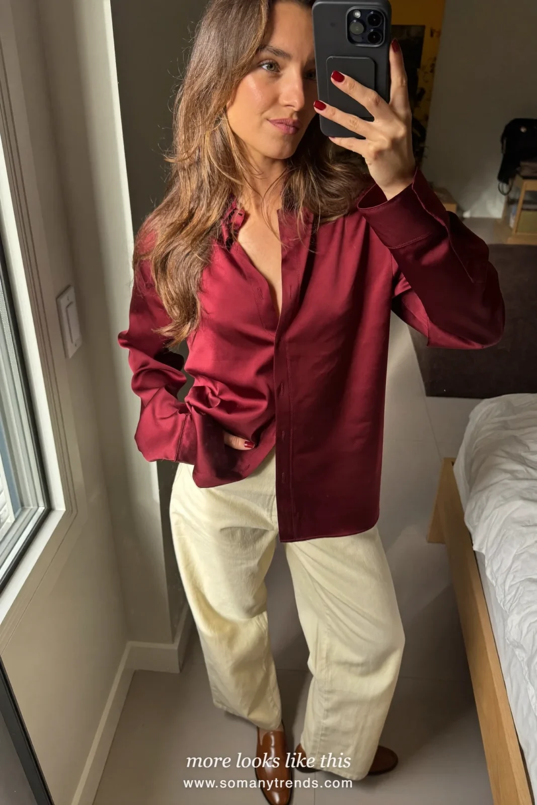 Woman in a burgundy shirt, cream wide-leg pants and cognac loafers in a conference atrium, work conference outfit 16