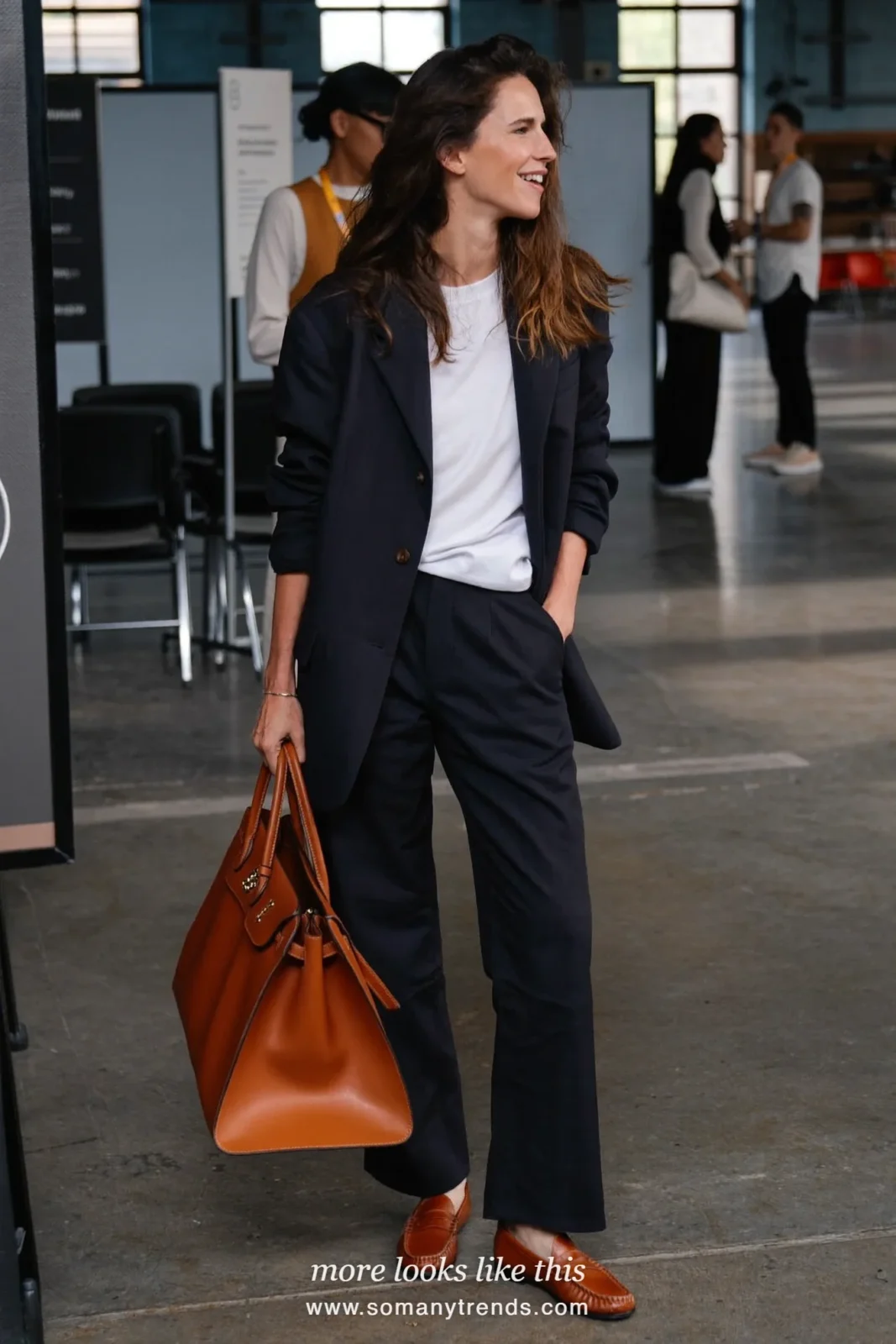 Woman in a navy blazer and wide-leg pants set with a white tee and cognac loafers at a conference, work conference outfit 23
