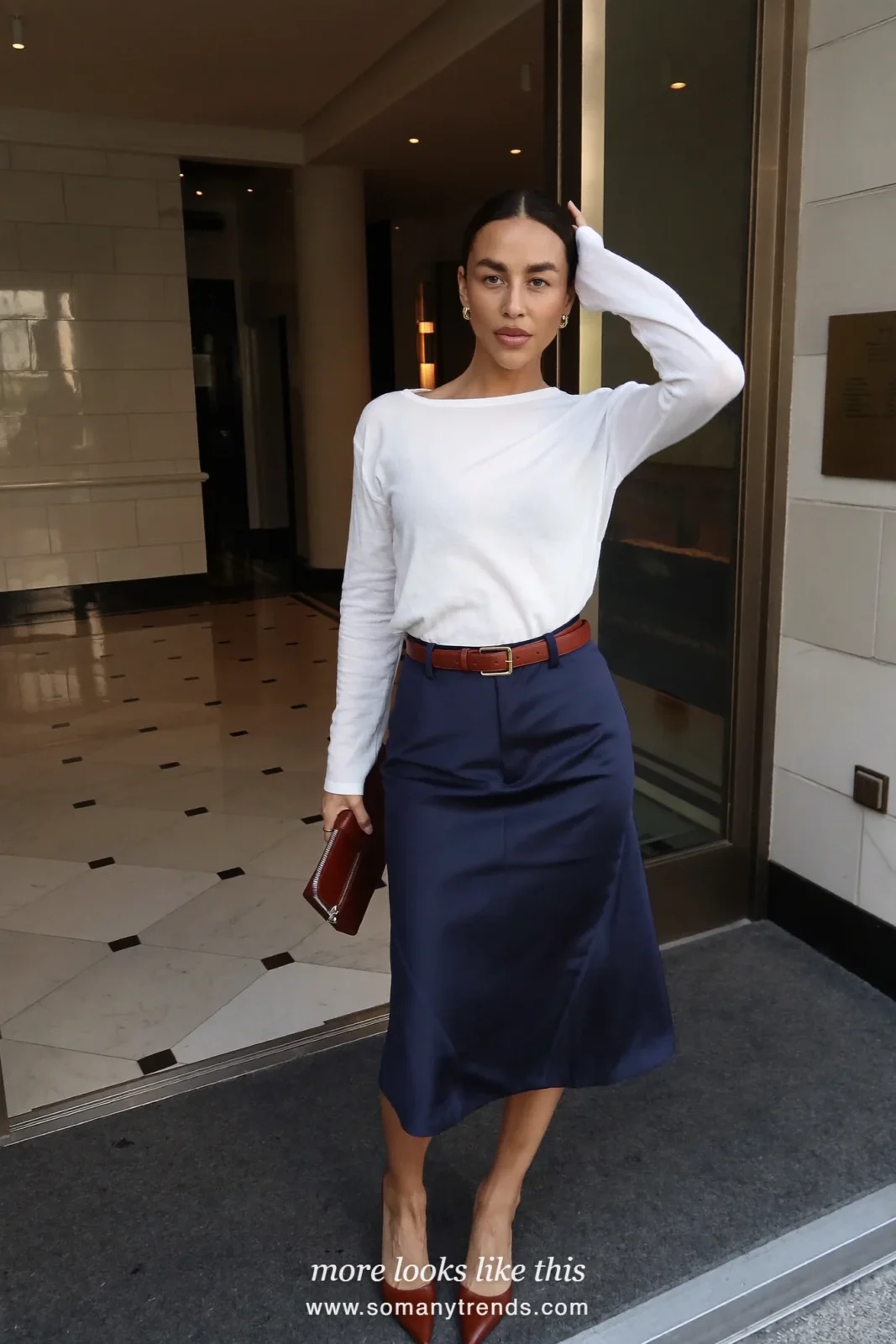 Woman in a navy satin midi skirt, white knit top, cognac belt and pointed pumps at a reception, work conference outfit 27