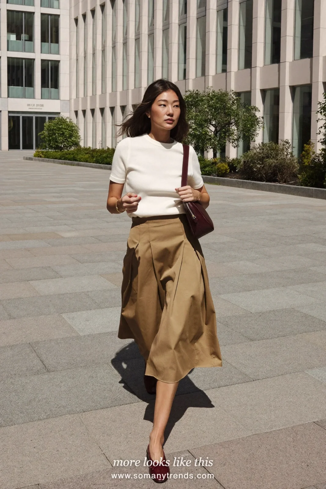 Woman in a camel poplin A-line midi skirt, white fine knit tee and burgundy flats, first day at work outfit 9