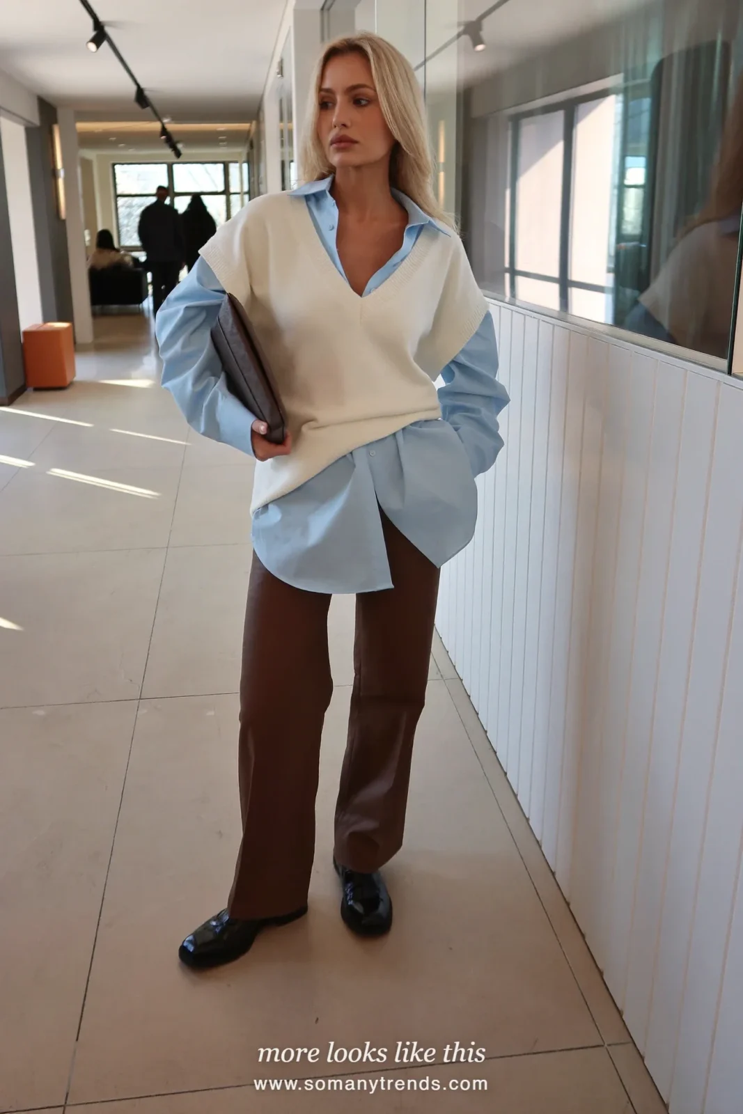 Woman in a light blue crisp shirt, cream fine knit vest, chocolate brown wide-leg pants and black derby shoes, first day at work outfit 17