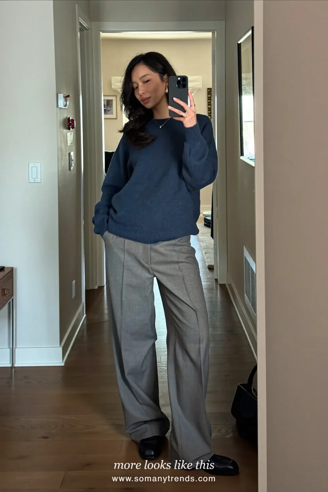 Woman in a camel belted wool-blend long coat over an ink blue fine knit, gray wide-leg pants and black loafers, first day at work outfit 24