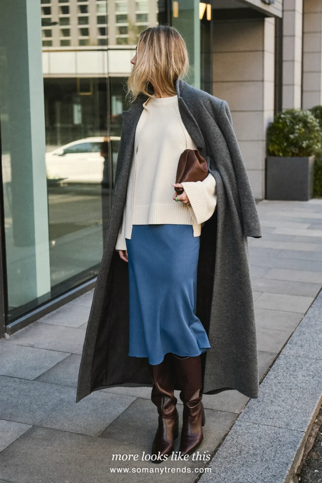 Woman in a long gray wool coat, ivory fine knit sweater, ink blue midi skirt and chocolate tall boots, first day at work outfit 26