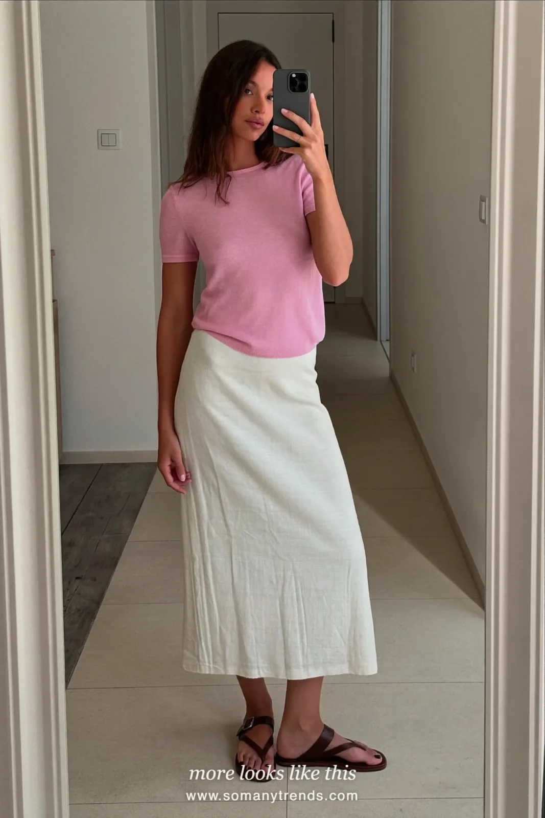 Look 4: pale pink knit top with a long white column skirt, mirror selfie at home in the hallway