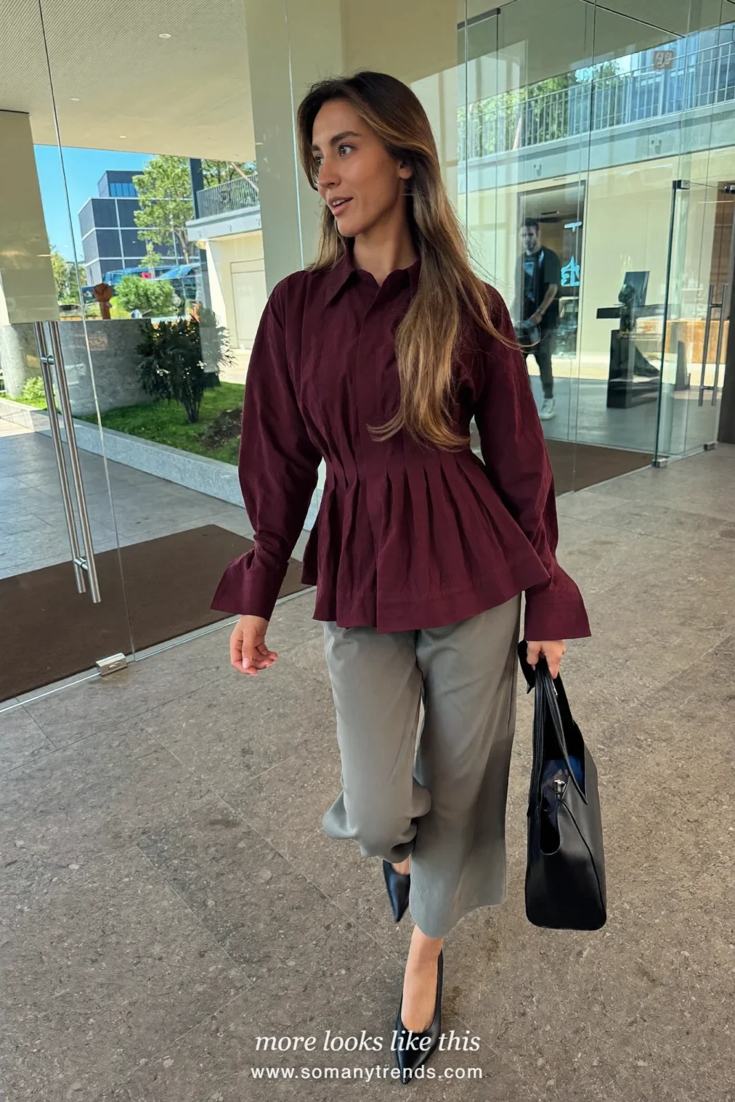 Woman in a burgundy crepe peplum blouse, gray relaxed wide-leg pants and black pointed flats, first day at work outfit 2