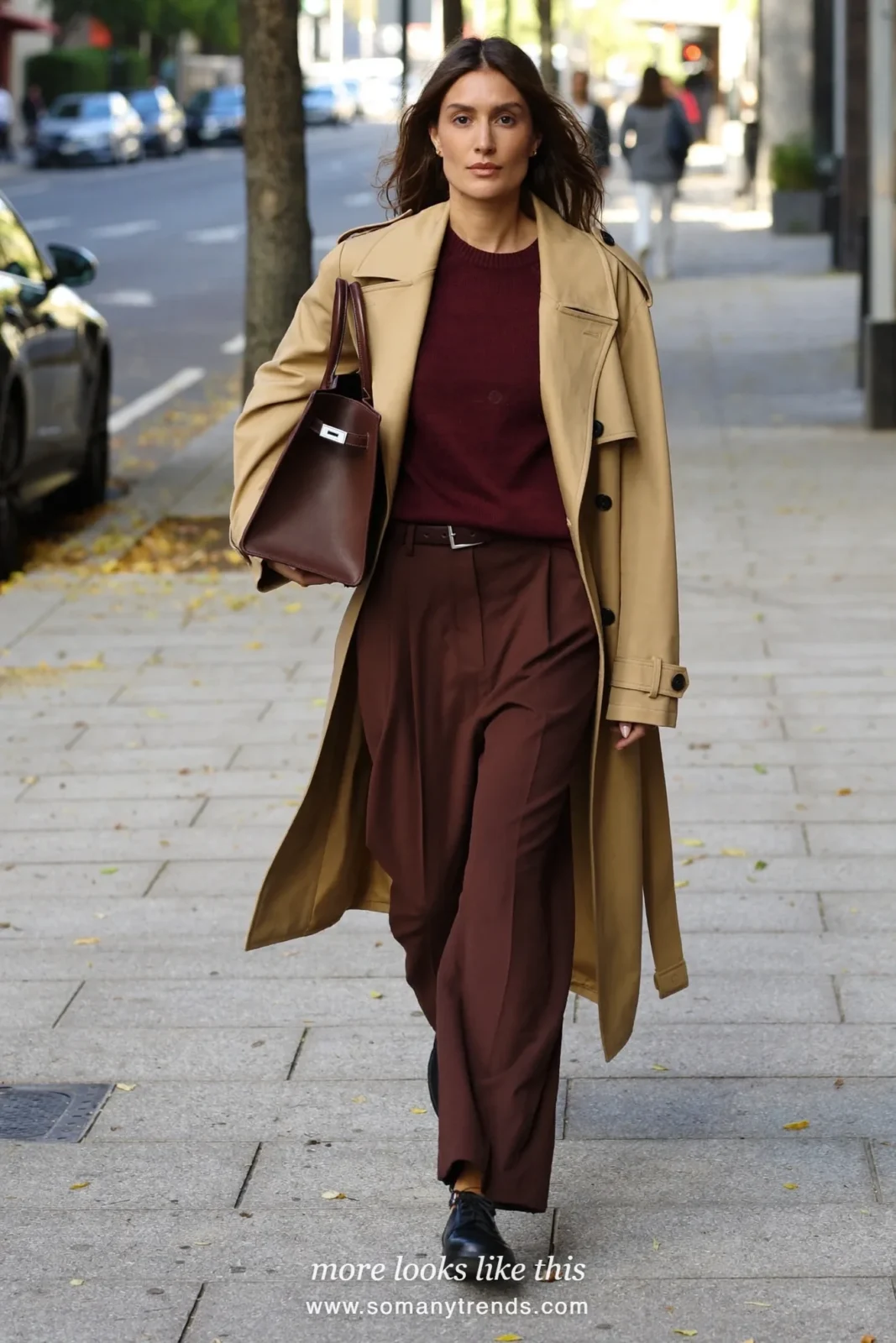 Woman in a camel trench coat over a burgundy fine knit, chocolate brown straight pants and black derby shoes, first day at work outfit 25