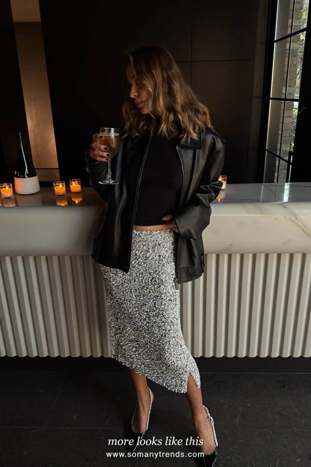 Woman in a black leather jacket, black fitted knit, beaded midi skirt and crystal slingback heels at a candlelit bar, outfit 3