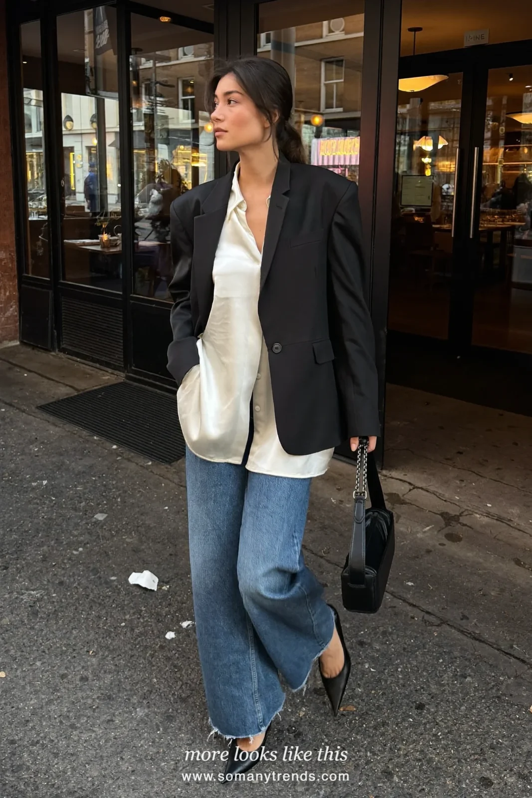 Woman in a cream satin blouse, relaxed black blazer, classic blue jeans and black pointed pumps, outfit 5