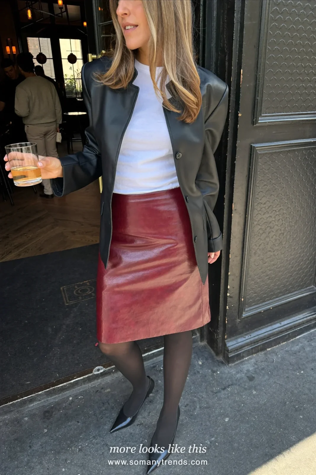 Woman in an oxblood leather skirt, white tee, black blazer and black pumps at a holiday party, look 10
