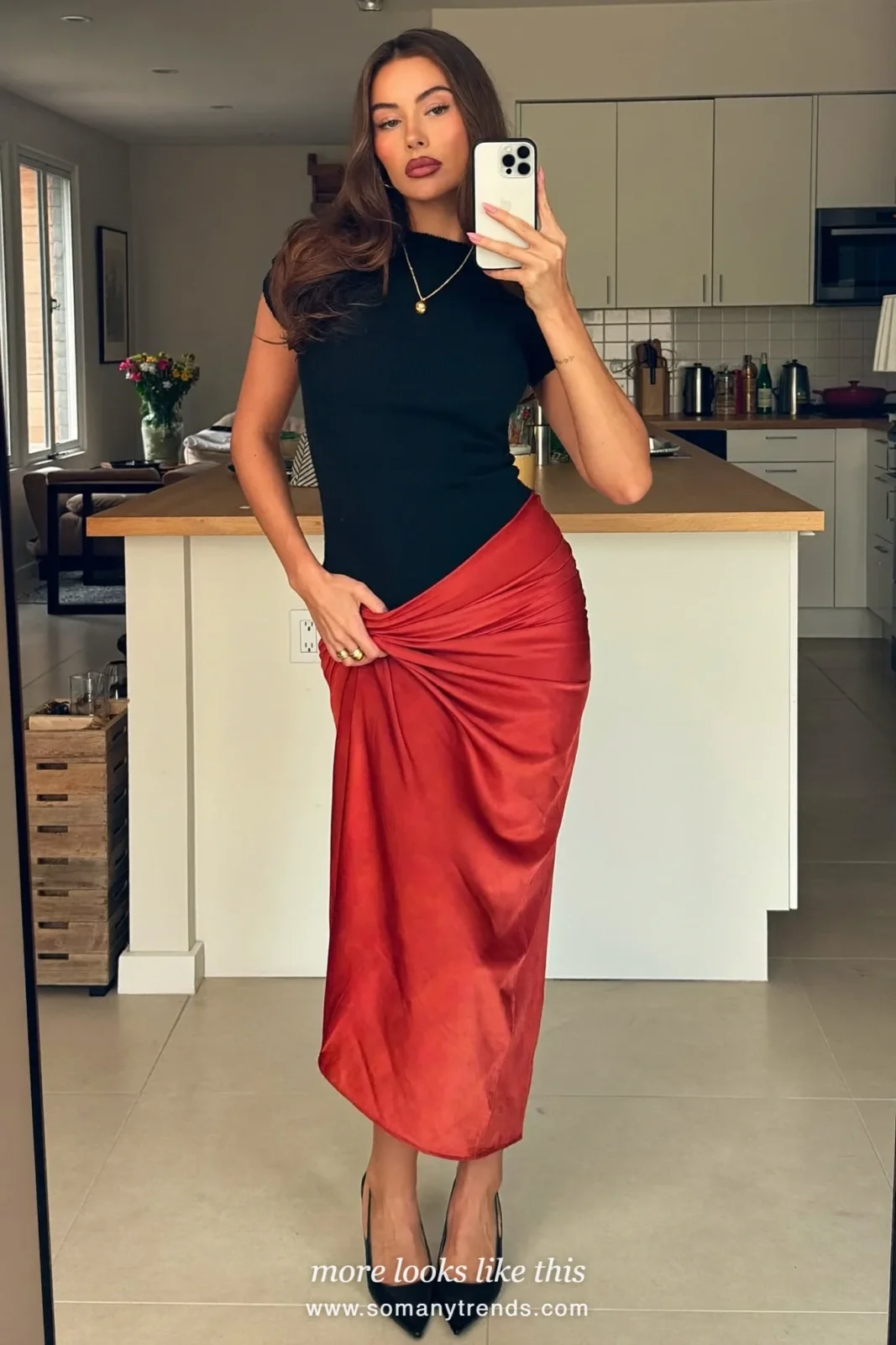 Woman in a red draped satin midi skirt, black fitted knit top and black heels taking a mirror selfie, party outfit 28