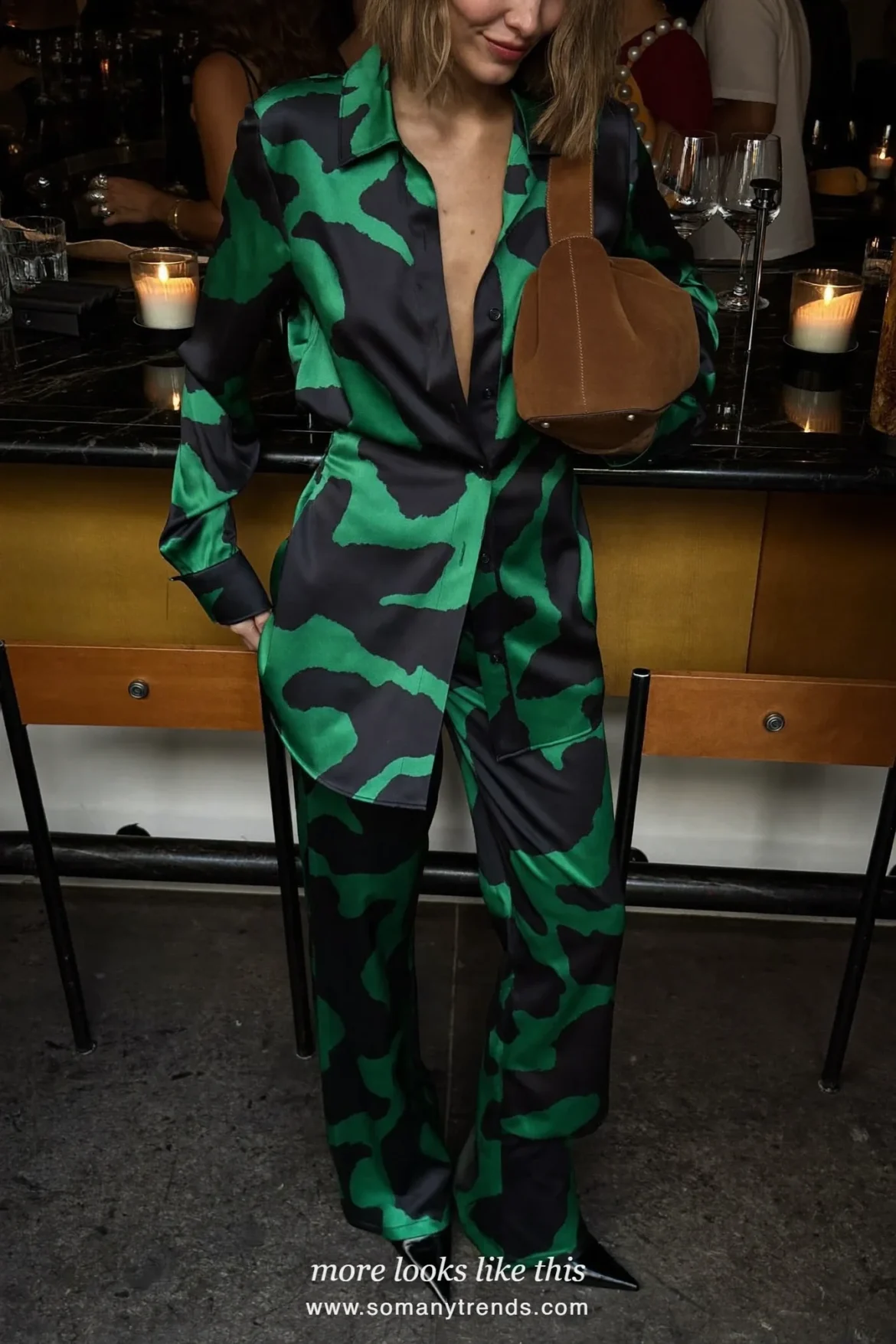 Woman in a swirl-print satin shirt and wide-leg pants set with a suede bag and pointed pumps at a bar, outfit 9