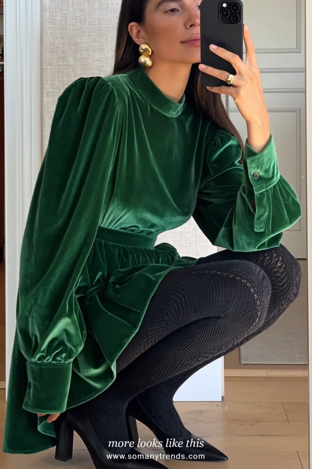 Woman in an emerald velvet midi dress, gold statement earrings, sheer tights and block-heel pumps by a Christmas tree, outfit 16