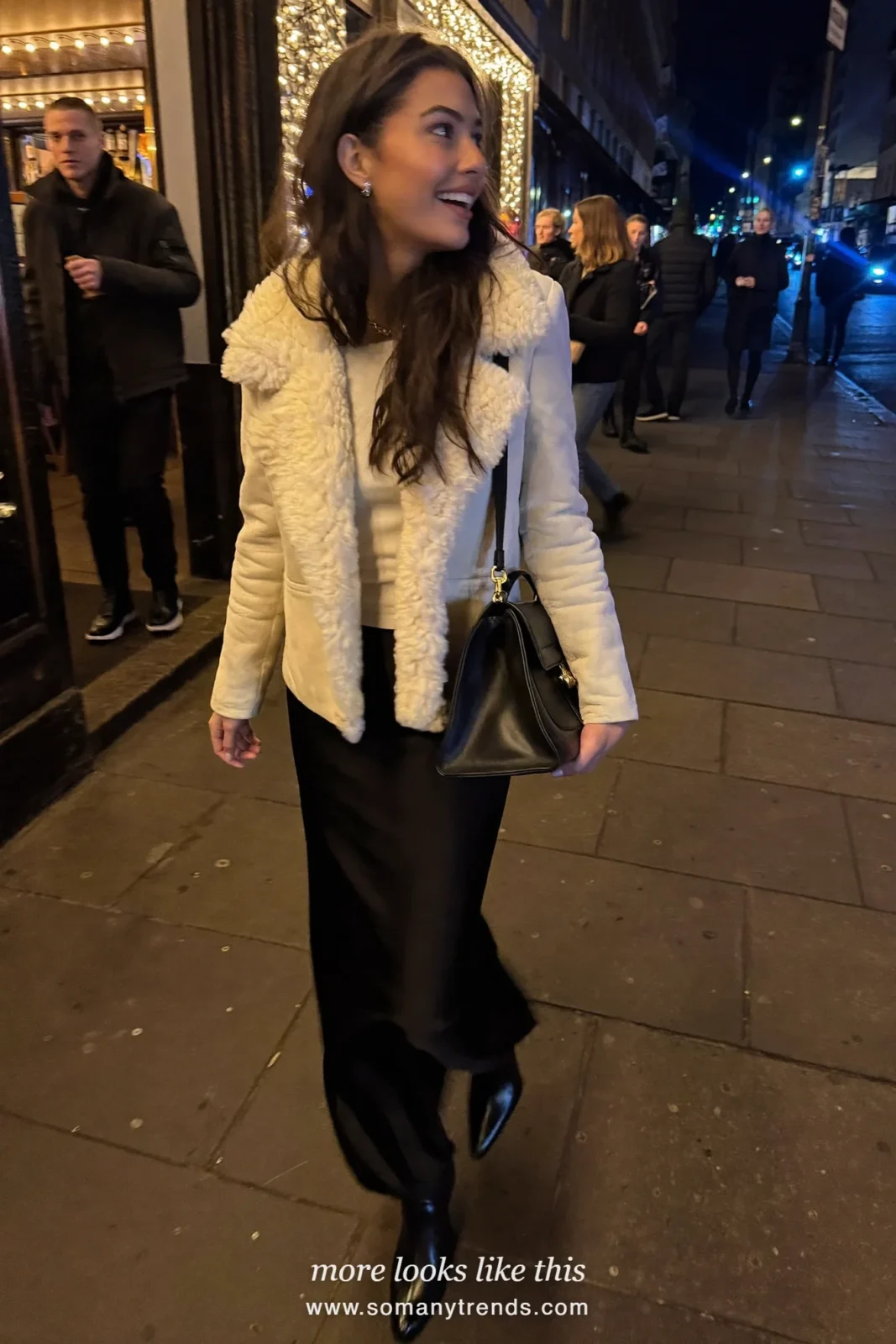 Woman in a shearling jacket, black crepe maxi skirt, white knit and heeled boots arriving at a pub, outfit 17