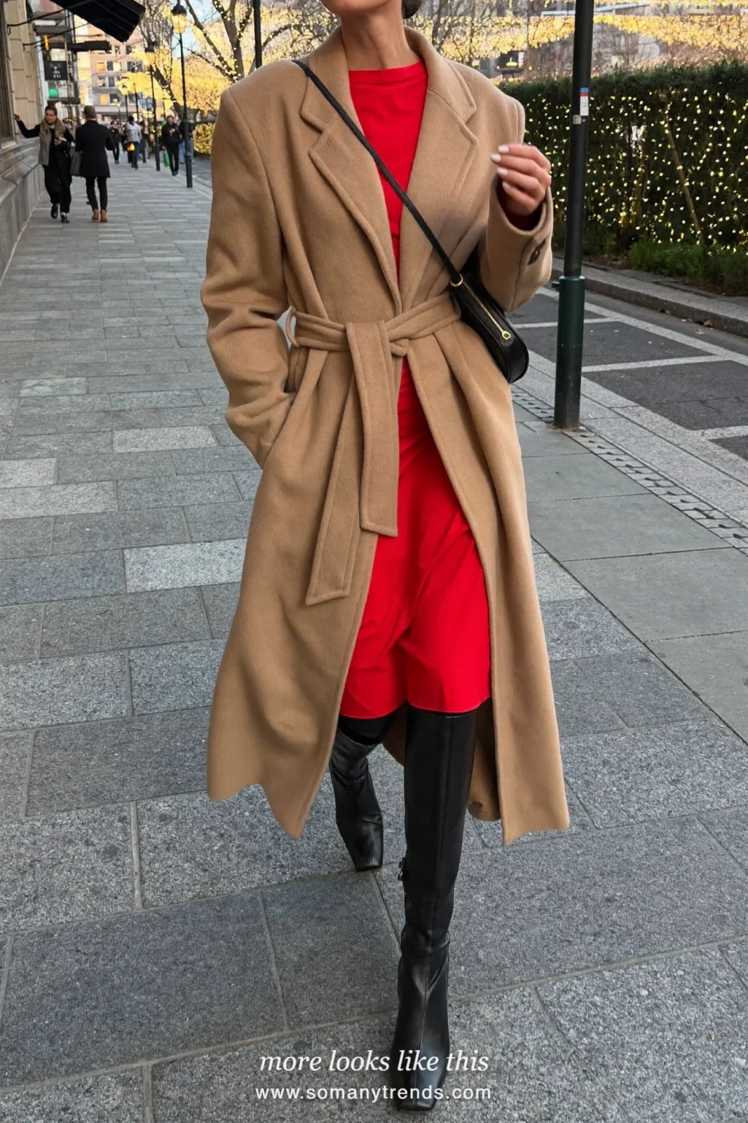 Woman in a long camel coat over a red dress with black tights and tall boots on a snowy street, outfit 21