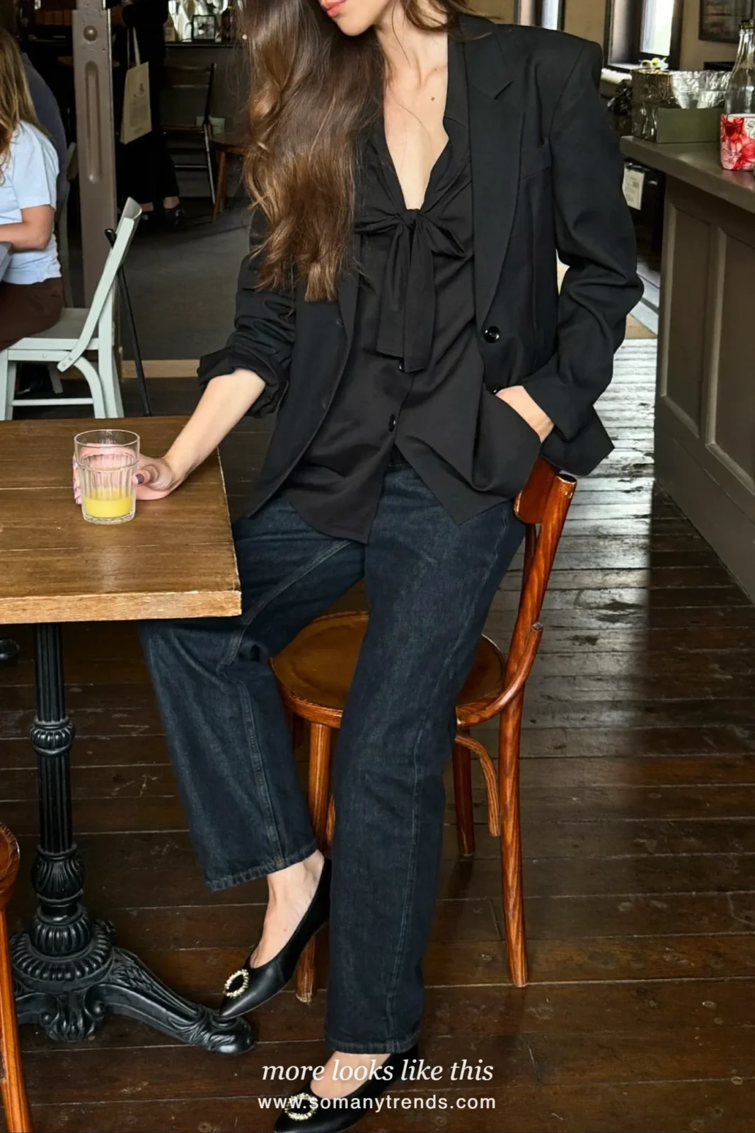 Woman in dark straight jeans, black blouse, blazer and embellished ballet flats at a pub table, outfit 26