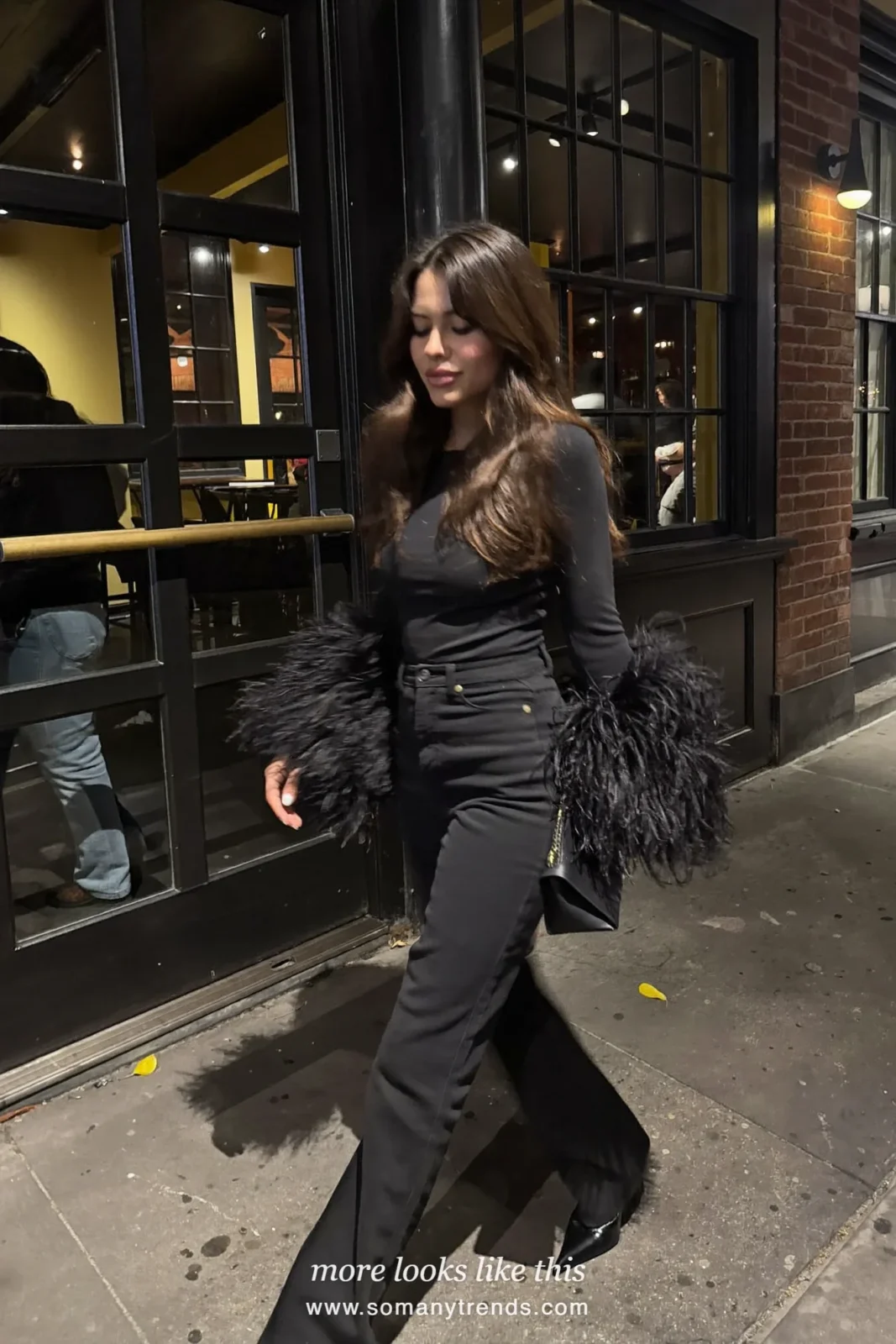 Woman in a black top with feather trim cuffs, straight black jeans and black pointed heels, outfit 9