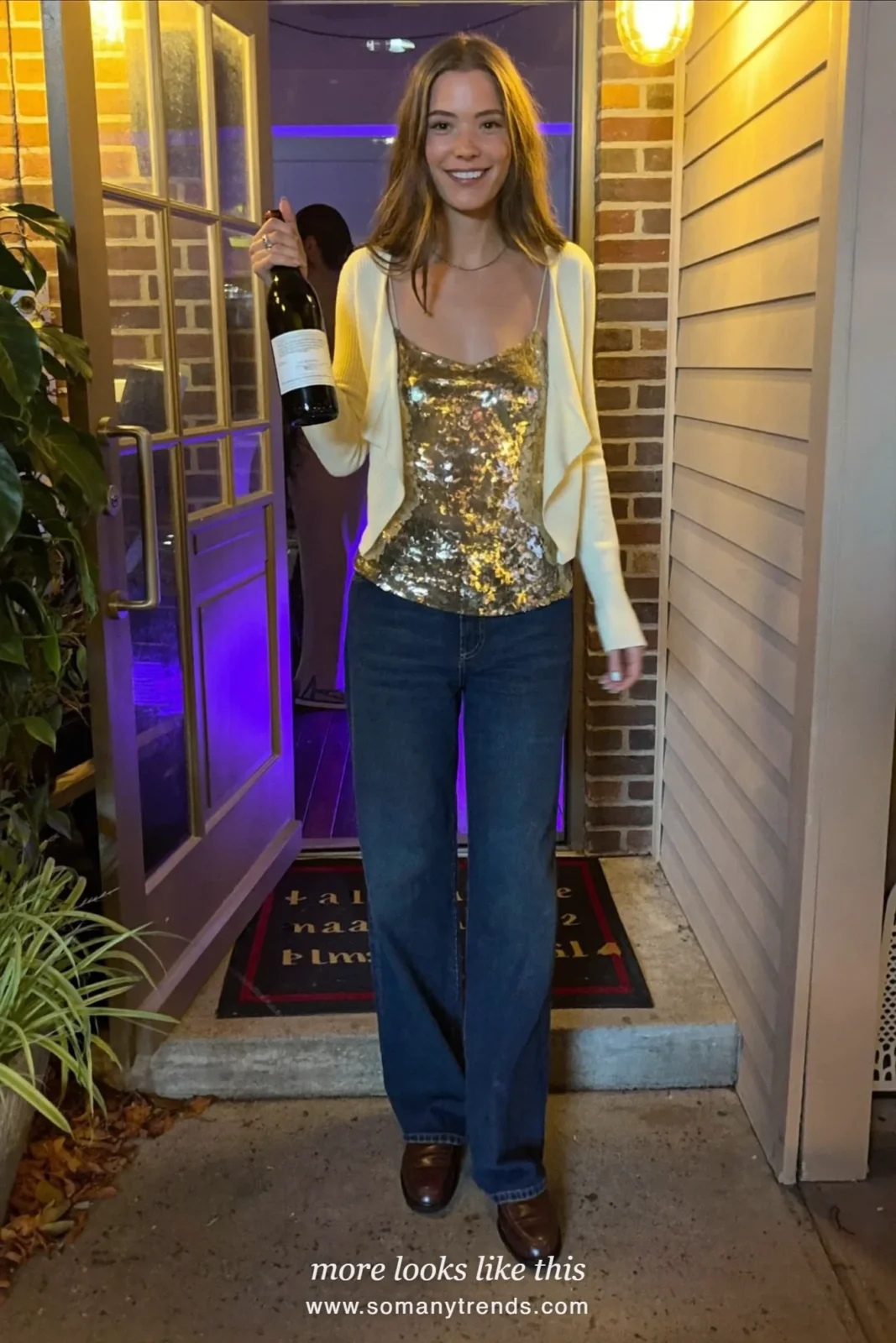 Woman in a champagne sequin camisole, cream fine-knit cardigan, dark straight jeans and brown loafers, outfit 15