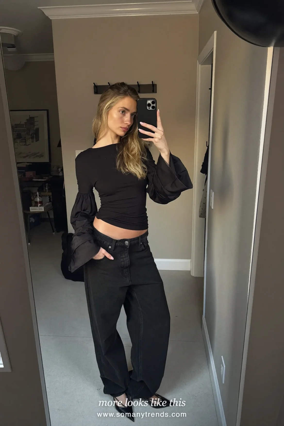 Woman in a black top with sheer organza sleeves, straight black jeans and black slingback heels, outfit 16