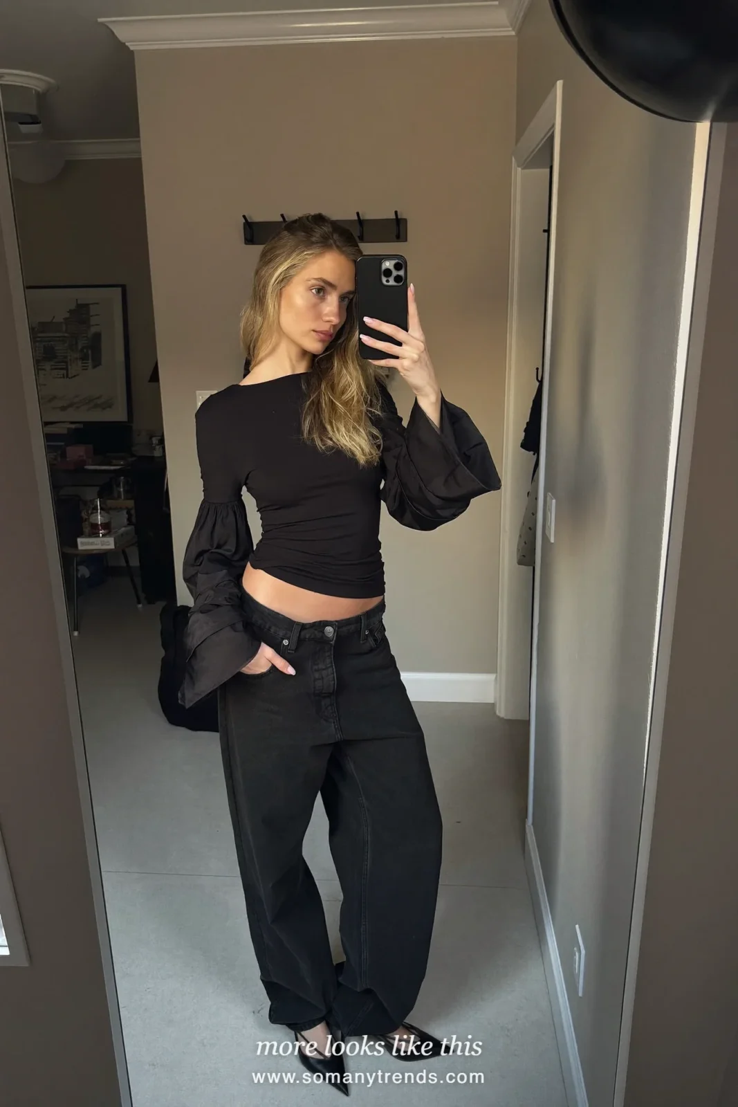 Woman in a black top with sheer organza sleeves, straight black jeans and black slingback heels, outfit 16