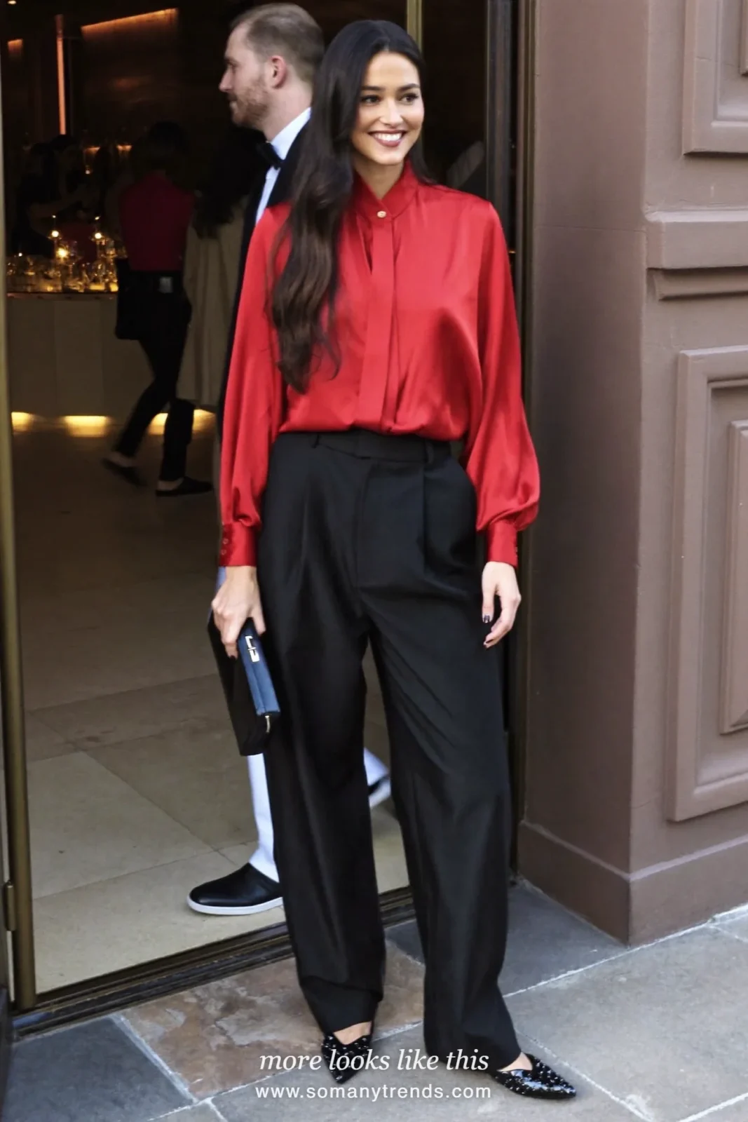 Woman in an oxblood satin blouse, black wide-leg pants and embellished black flats at a holiday party, look 7