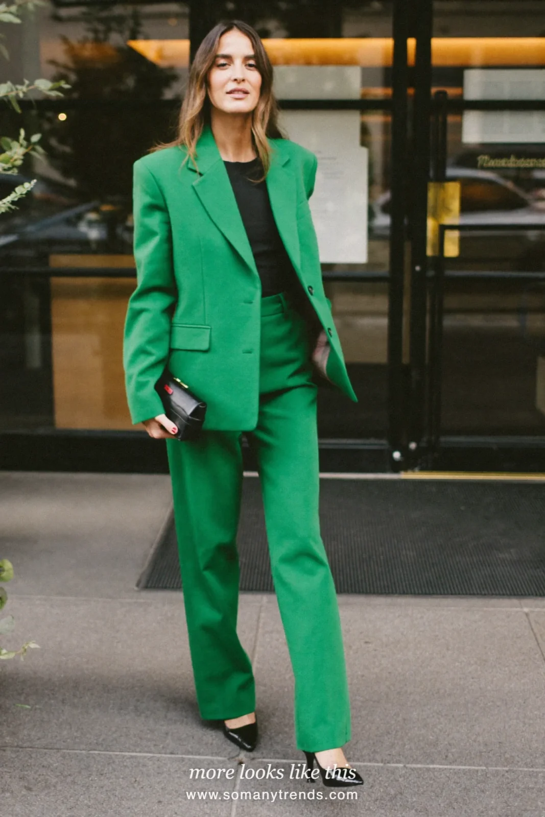 Woman in an emerald green blazer and pants set with a black top and black pumps at a holiday party, look 15