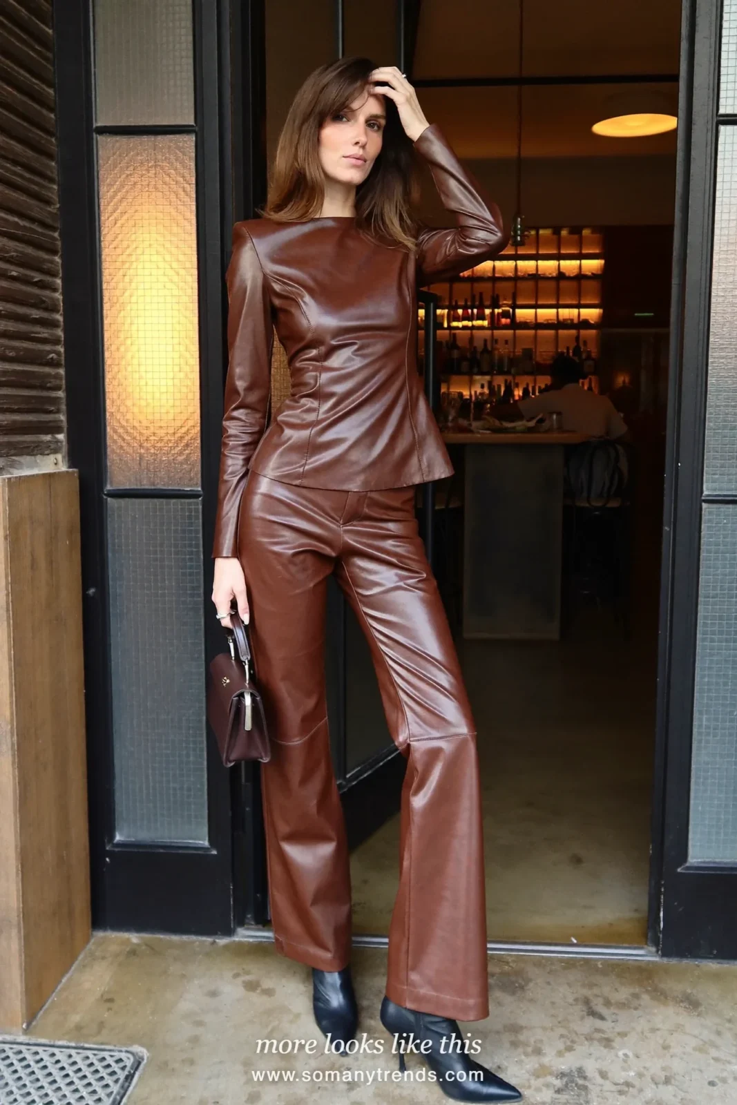 Woman in a chocolate brown faux leather top and pants set with heeled boots at a holiday party, look 17