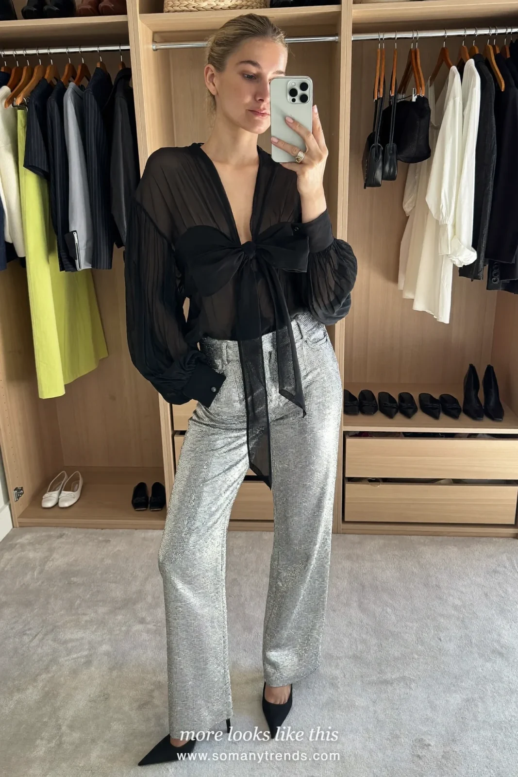 Woman in silver lurex wide-leg pants, black bow blouse and black pumps at a holiday party, look 24
