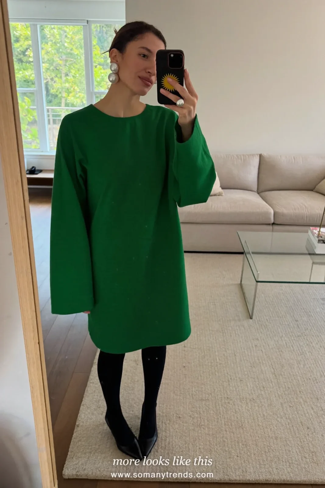 Woman in an emerald green dress, large pearl cluster earrings and black pumps at a holiday party, look 28