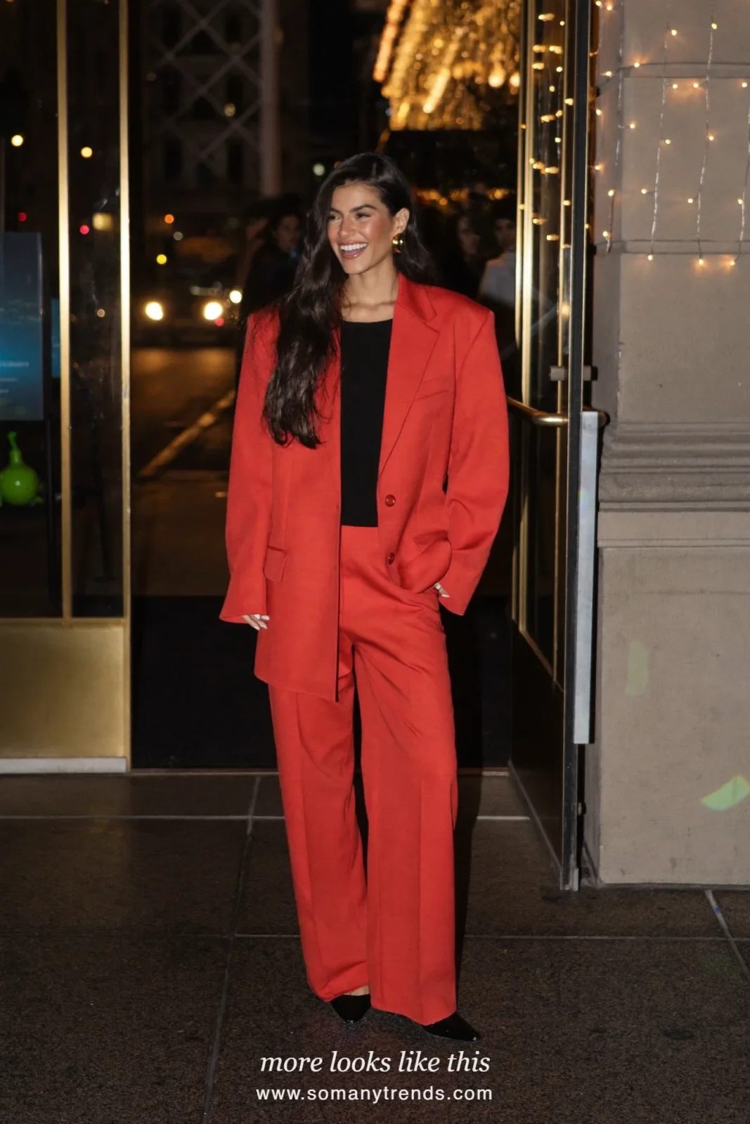 Woman in a tomato red blazer and straight-leg pants set with black top and black pumps, party outfit 3