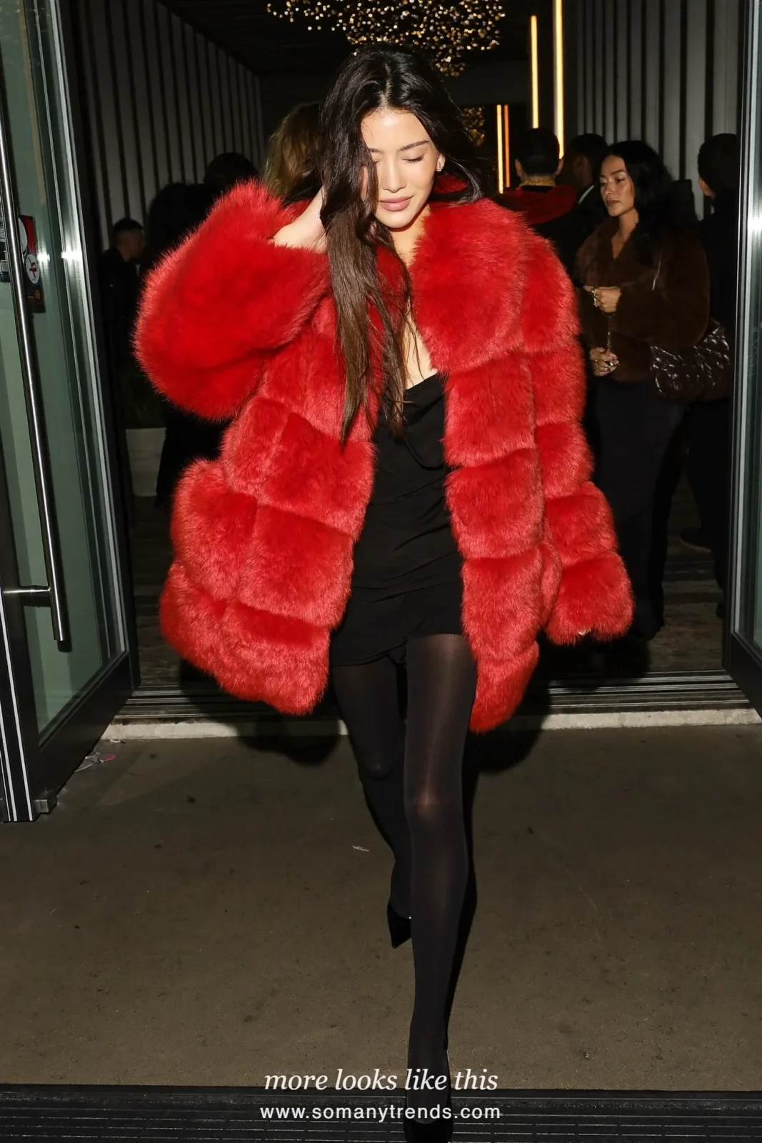 Woman in a tomato red faux fur coat over a black dress with sheer tights and black pumps, party outfit 9