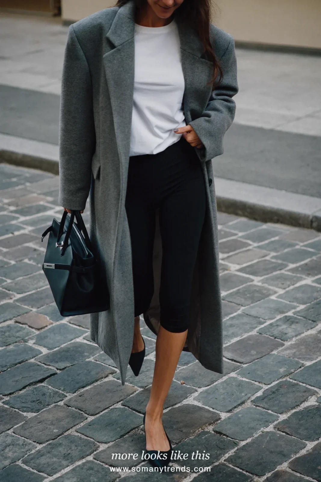 Woman in an oversized long gray wool coat, white tee, black leggings, pointed flats and a structured bag, look 7