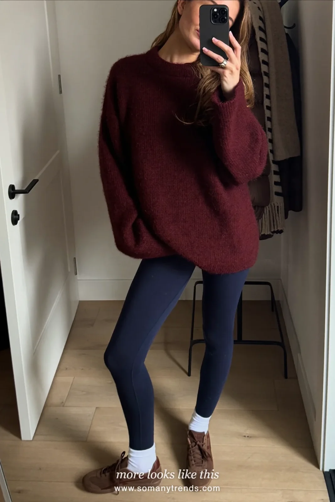 Woman in a burgundy sweater, navy leggings, white socks and brown suede sneakers with a black puffer, look 8