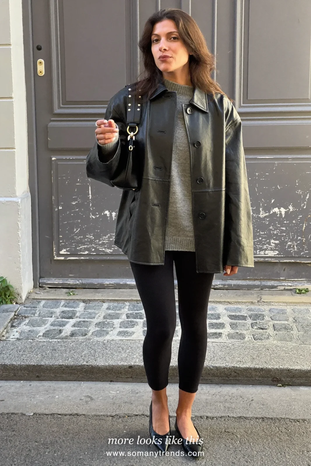 Woman in a relaxed black leather jacket, gray fine-knit sweater, black leggings and black pointed flats, look 13