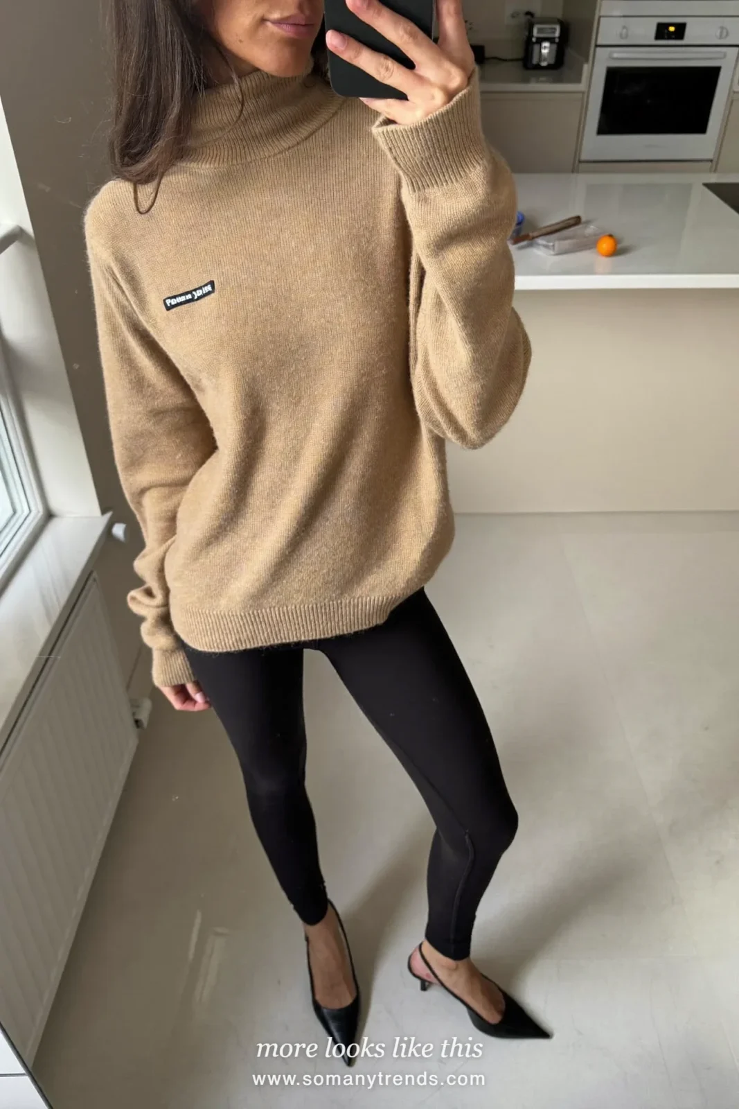 Woman in a camel turtleneck, black leggings, black slingback heels and a quilted black bag, look 20