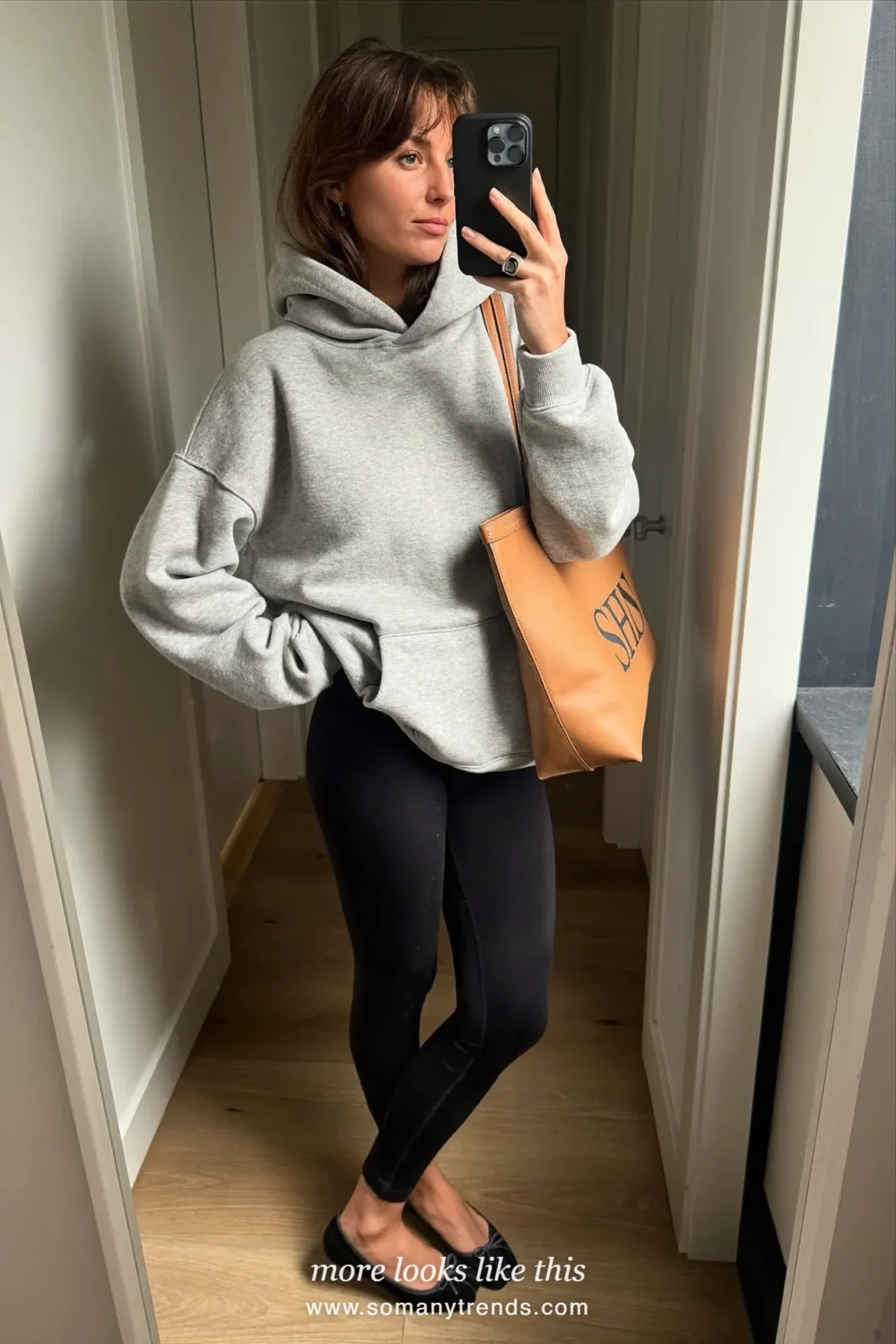 Woman in a gray hoodie, black leggings, black ballet flats and a leather tote, mirror selfie, look 24