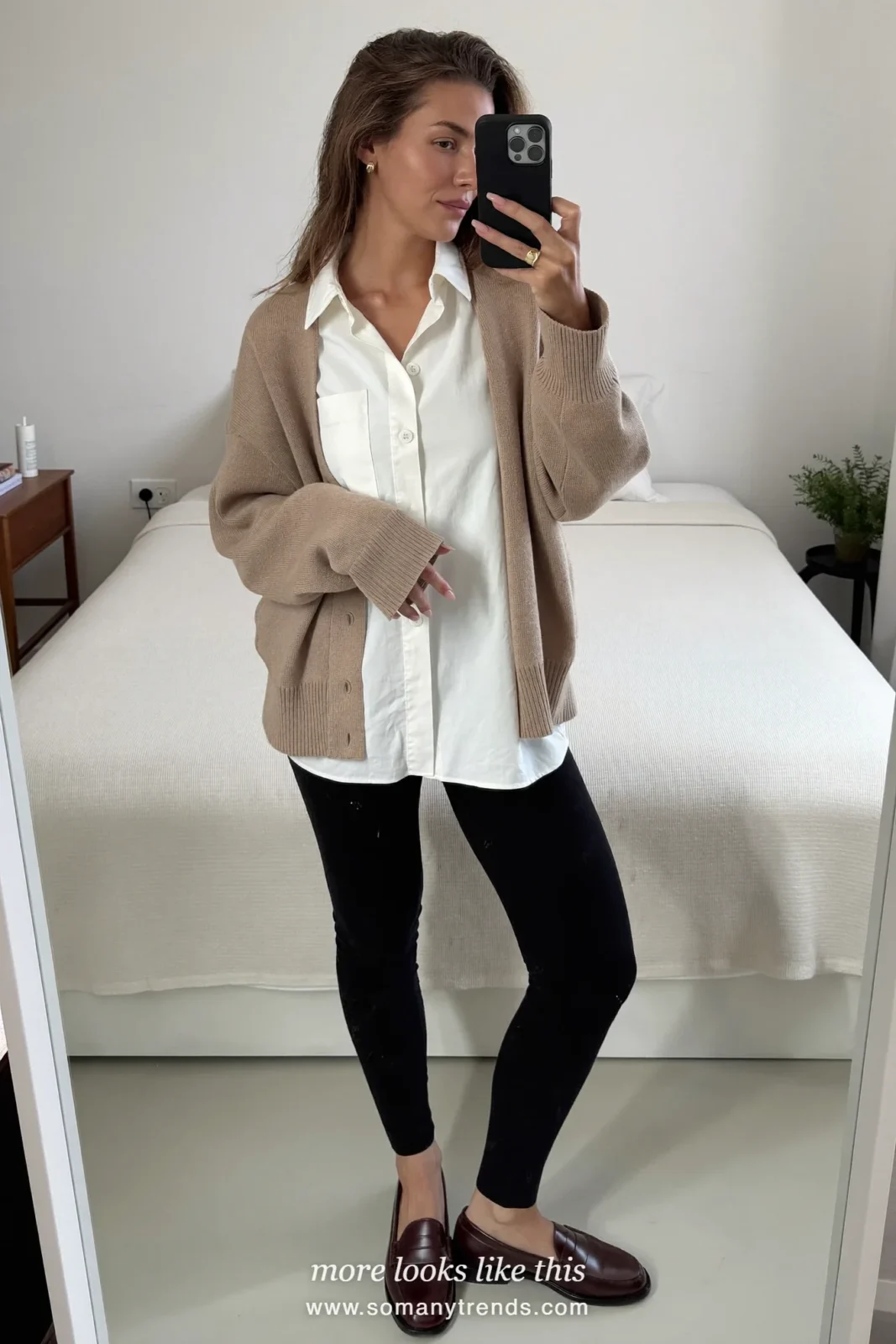 Woman in an oatmeal cardigan, white collared shirt, black leggings, brown loafers and a small leather bag, mirror selfie, look 12