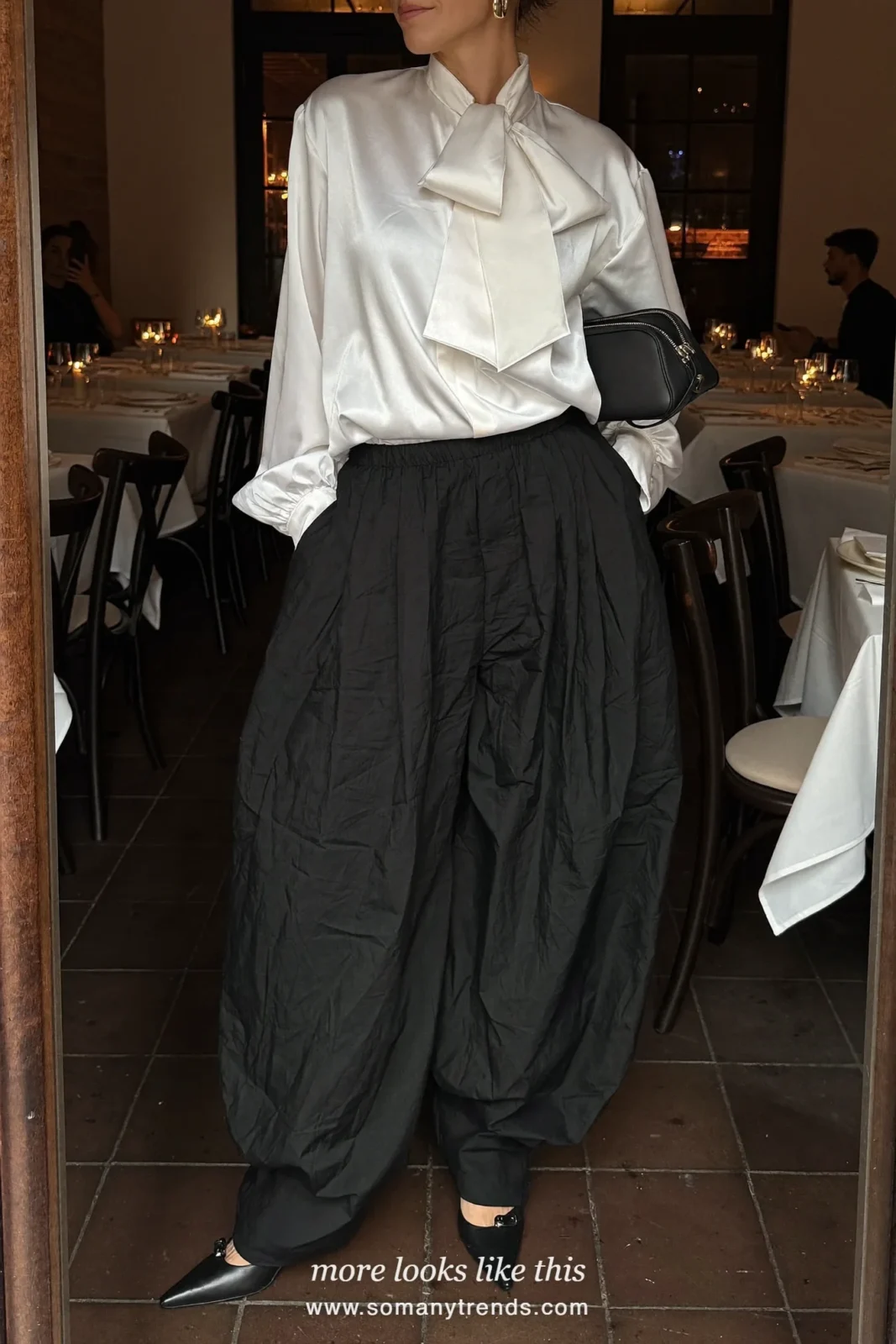 Woman in a white satin bow blouse, wide black pants and pointed pumps, cocktail outfit 27