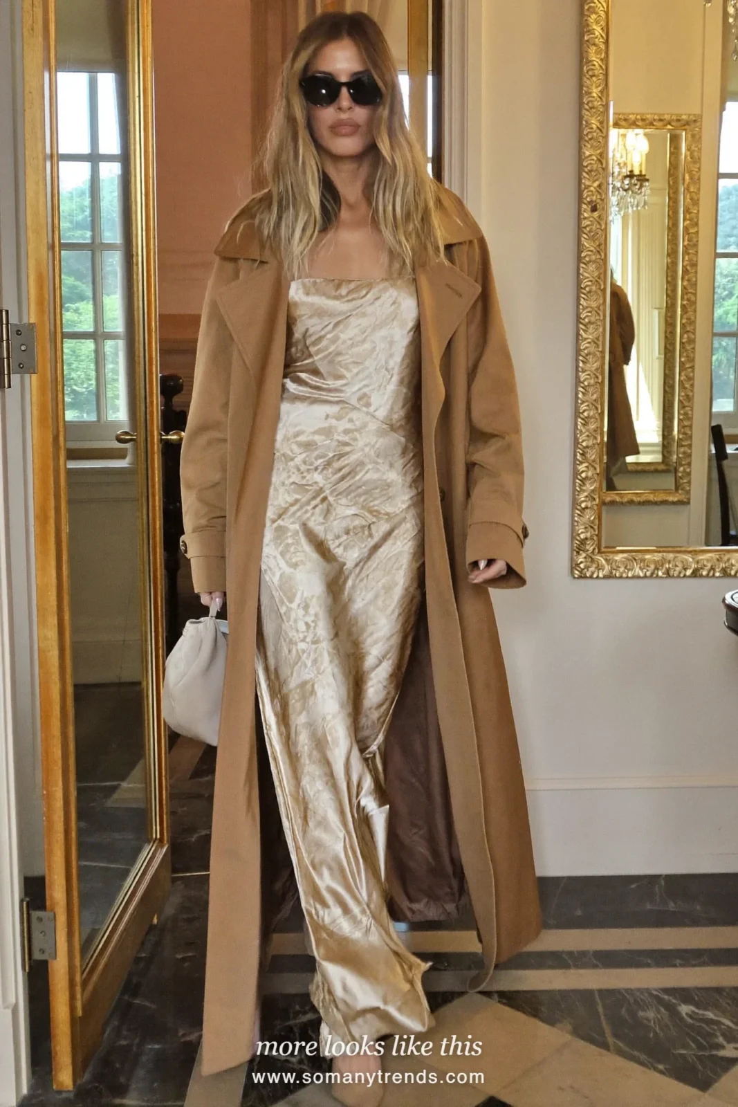 Woman in a long camel trench coat over a champagne satin maxi slip dress with dark sunglasses, cocktail outfit 15