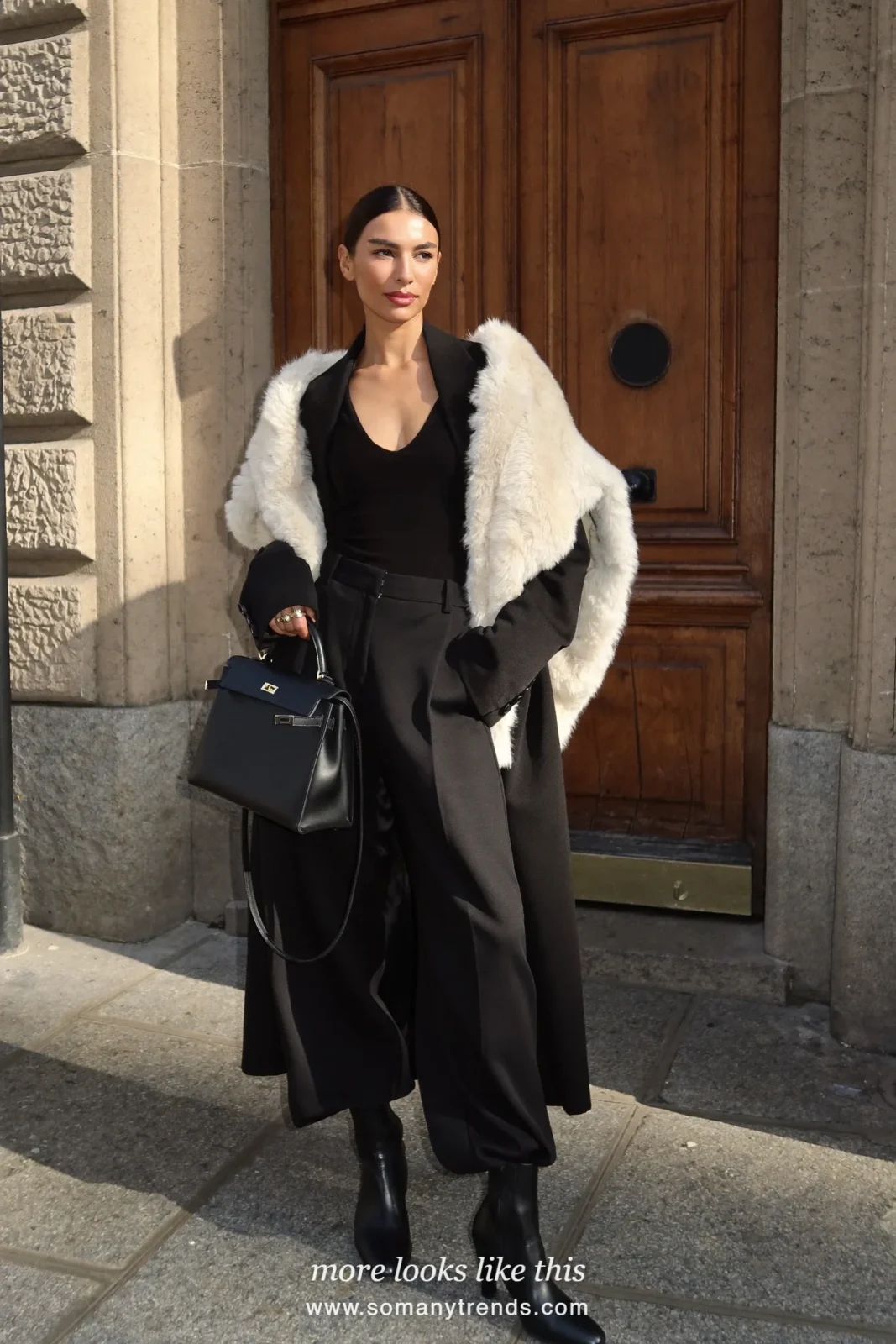 Long black wool coat with a cream faux-fur stole, black structured bag, black pants and black boots, outfit 15
