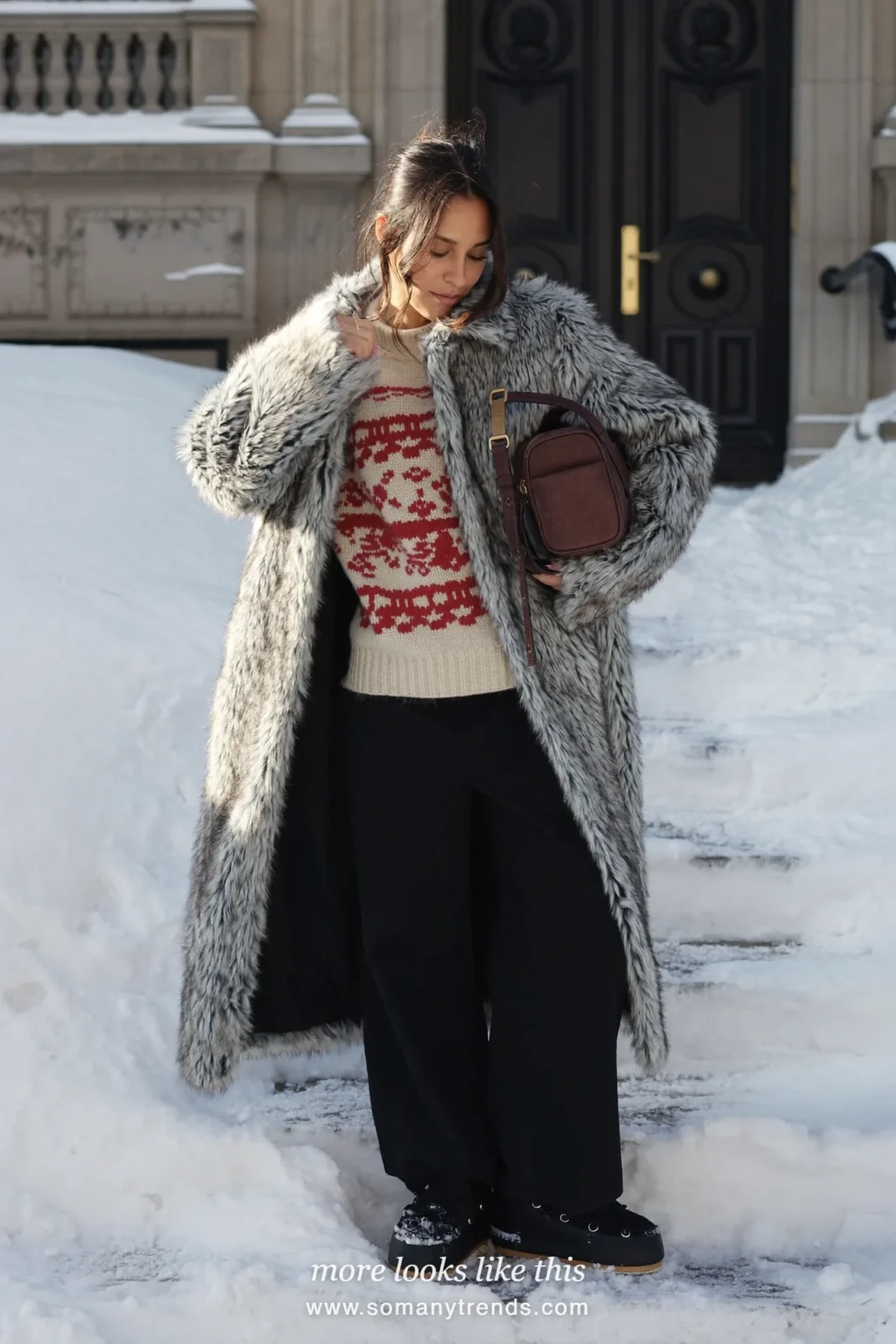 Faux-fur coat over printed chunky knit with straight black pants and snow boots on snowy steps, outfit 9