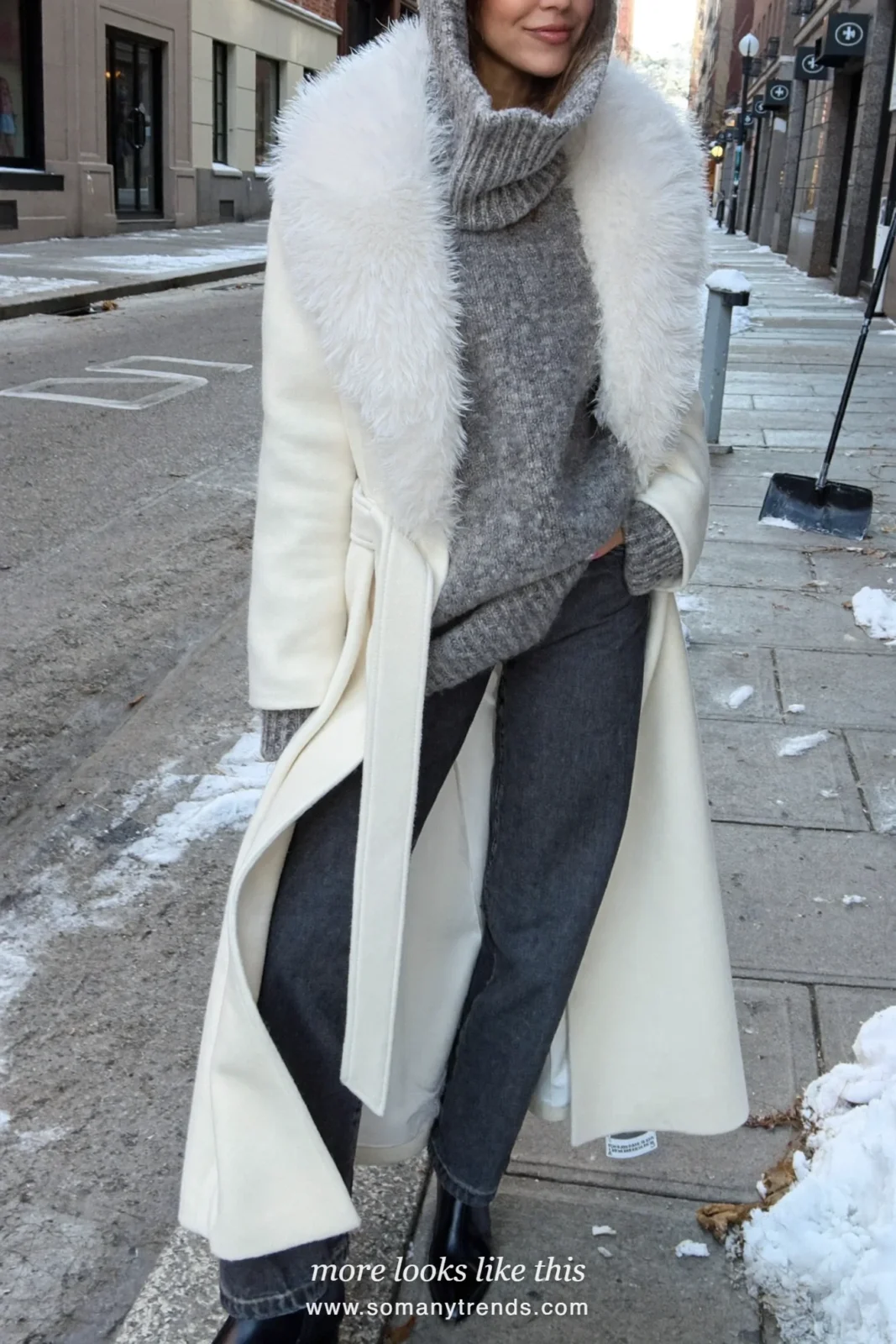 White belted coat with fur collar, gray knit hood, dark pants and black boots on a snowy street, outfit 11