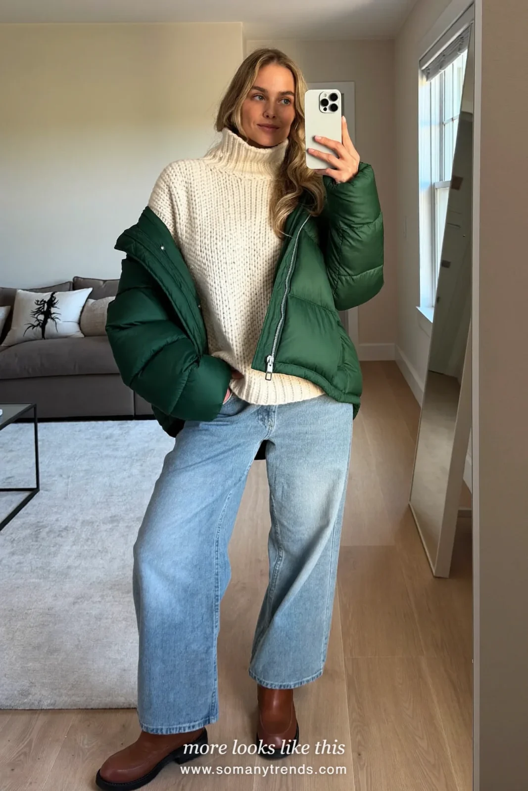 Forest green puffer jacket with cream sweater, wide light-wash jeans and brown boots in a snowy park, outfit 12