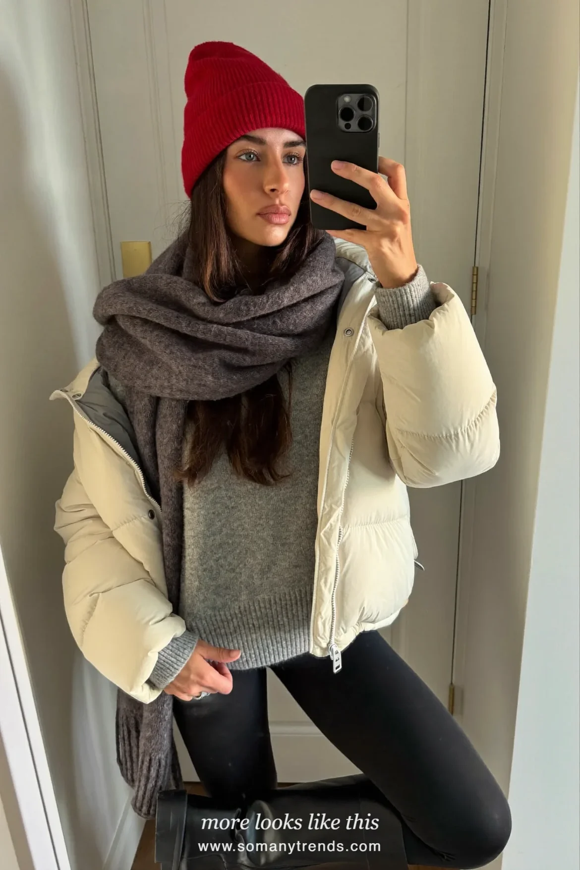 Cream puffer jacket with red beanie, gray scarf, black leggings and black boots on a snowy street, outfit 16