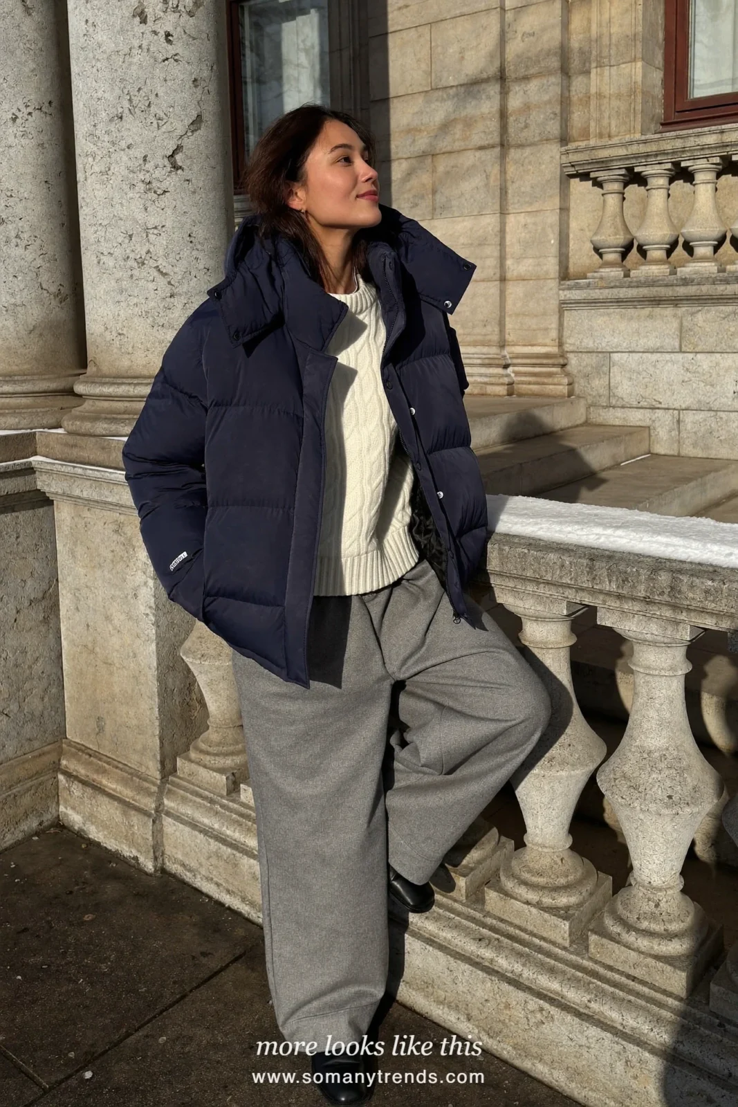 Navy puffer with white knit, wide gray flannel pants and black boots on snowy steps, outfit 18