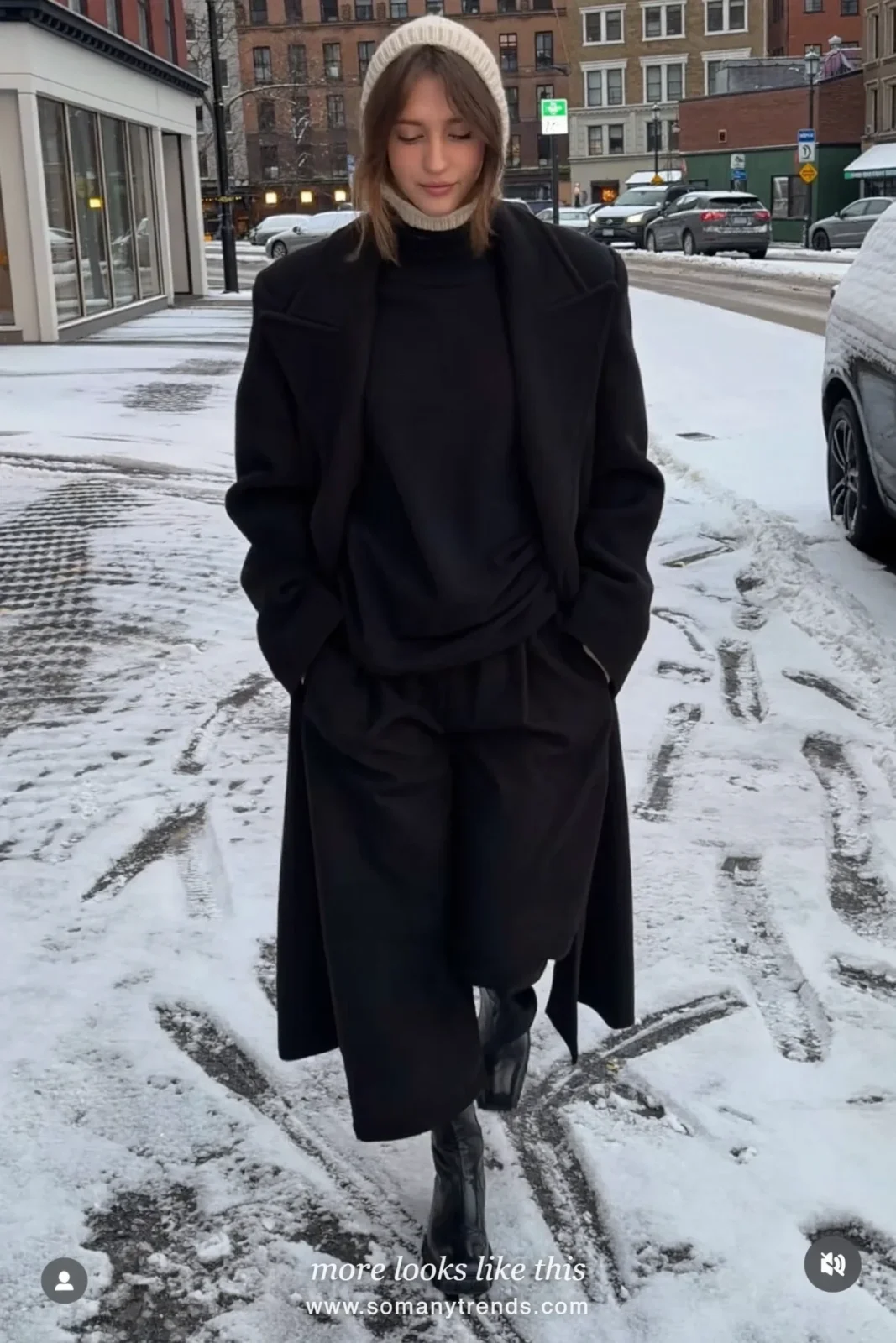 Long black coat with cream knitted hood, black pants and black boots on a snowy street, outfit 19